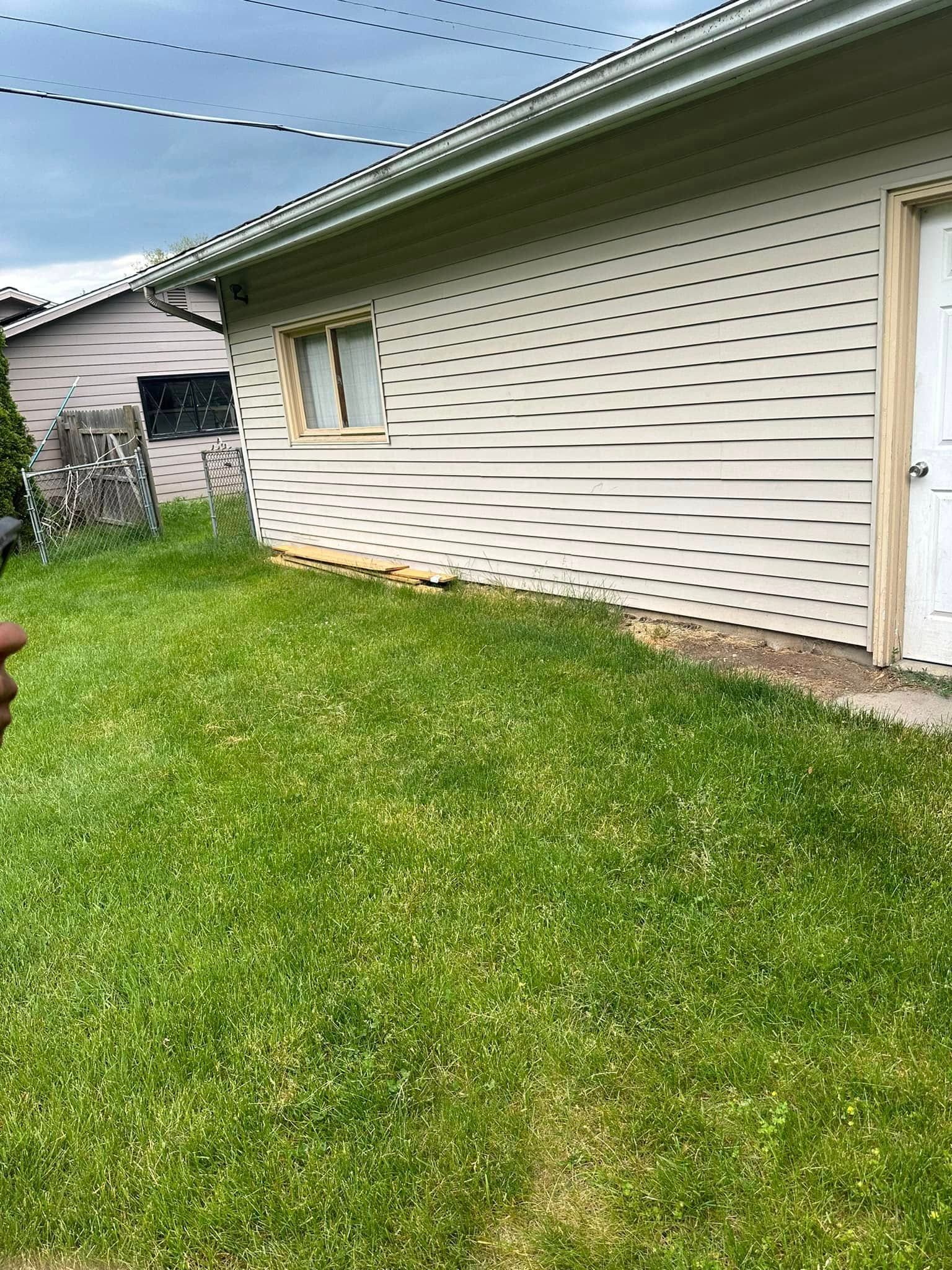 Lawn and exterior of building with window and door. Overcast sky.