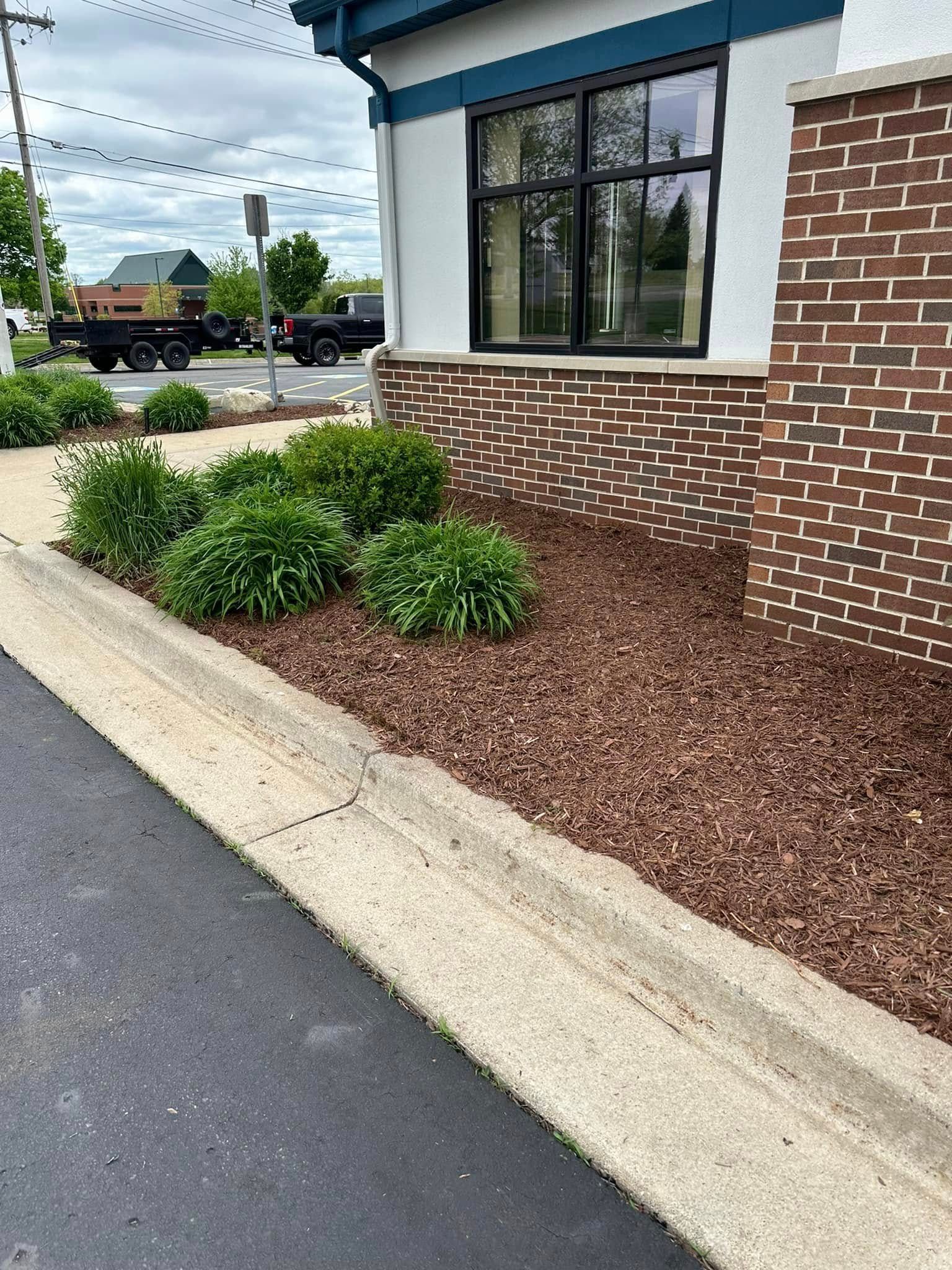 A curb with a planted garden bed next to a brick building.