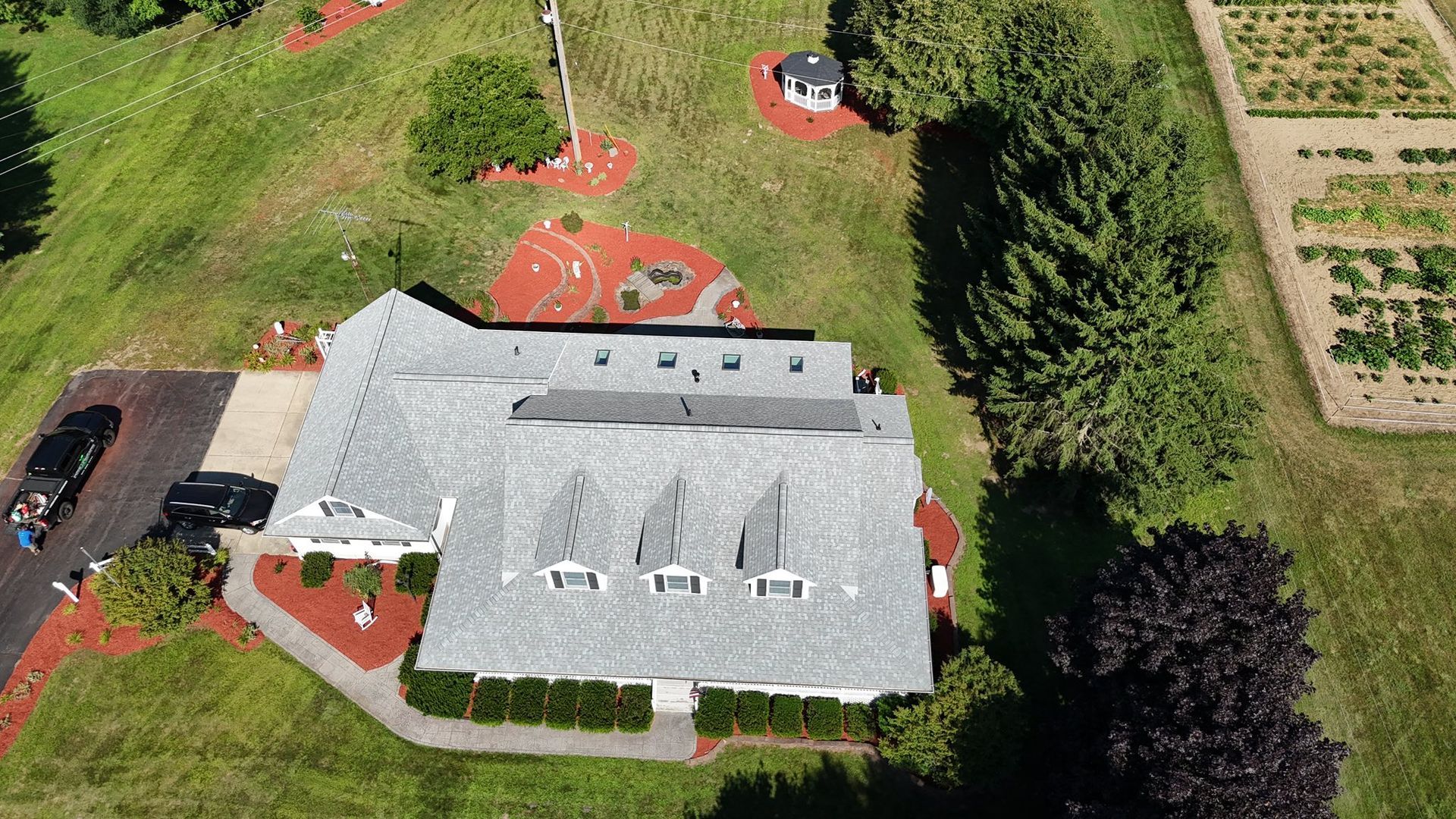 Planter with green shrubs and brown mulch bordered by a concrete walkway.