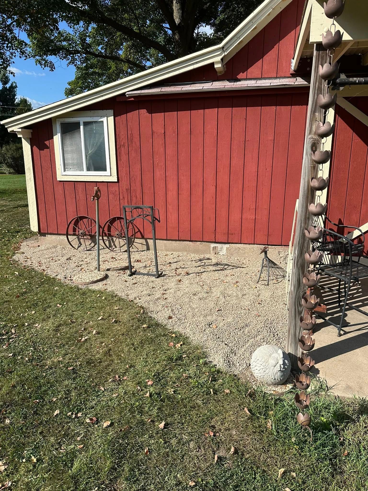 Red building with window, gravel bed, and decorative metal bike sculpture.