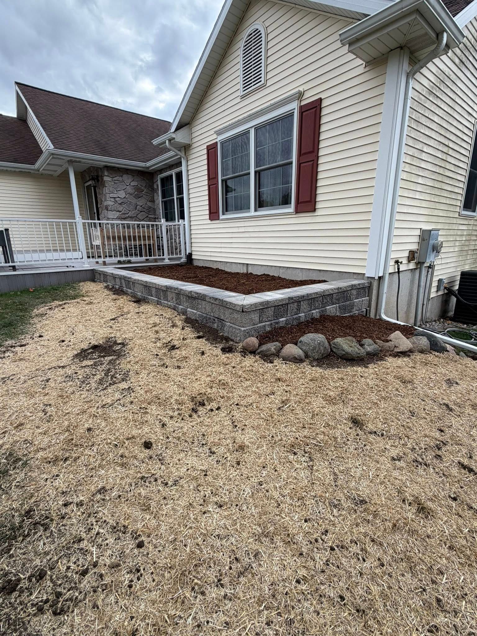 House exterior with a raised garden bed filled with mulch.