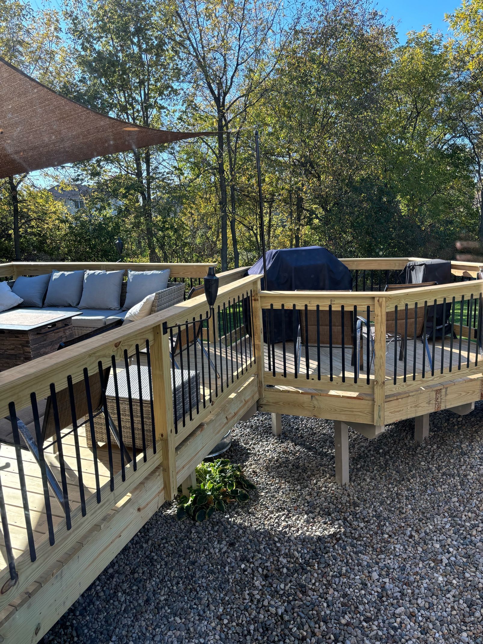 A wooden deck with a couch and a grill on it.