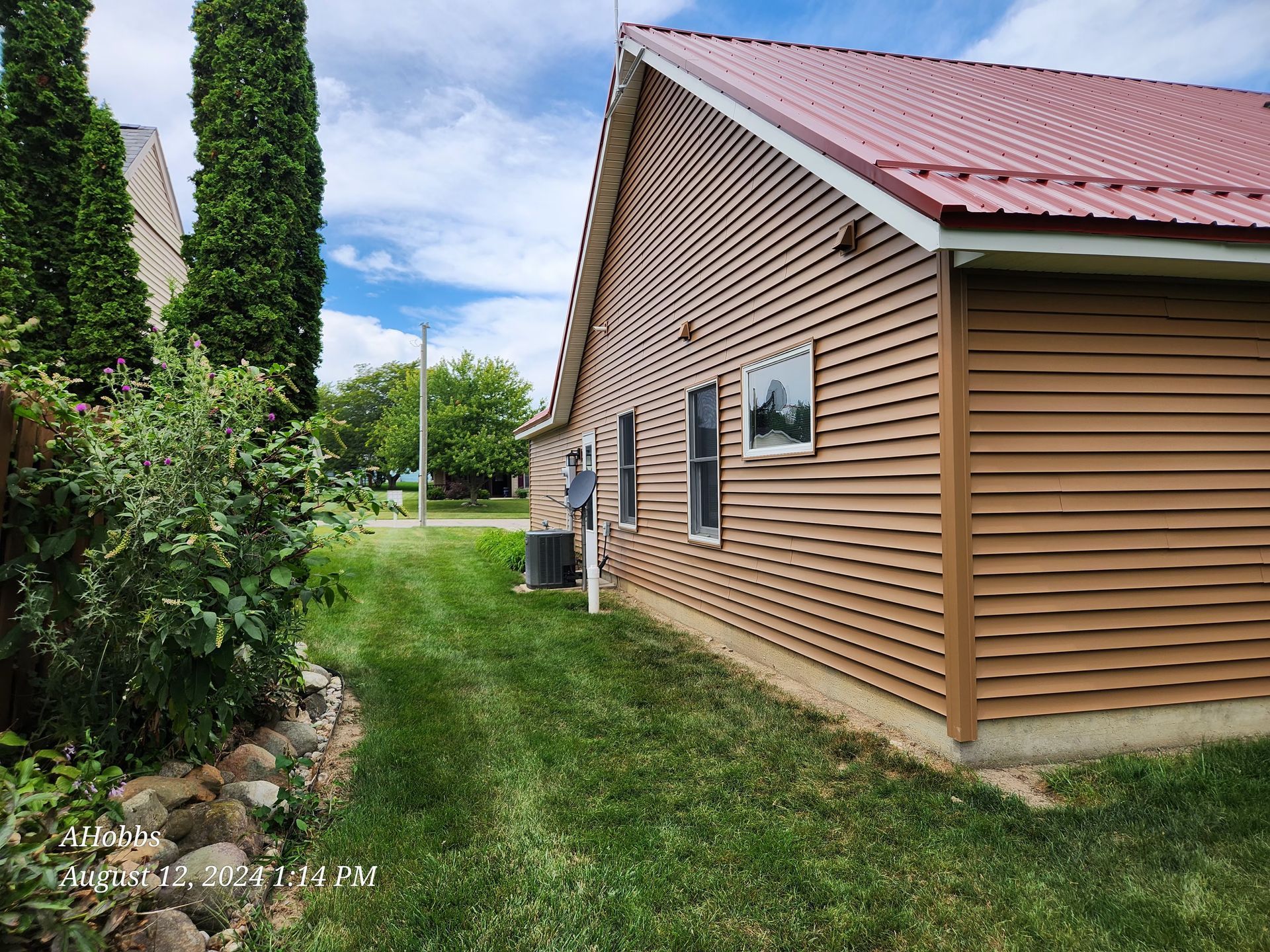 A house with a red roof and wooden siding is for sale.