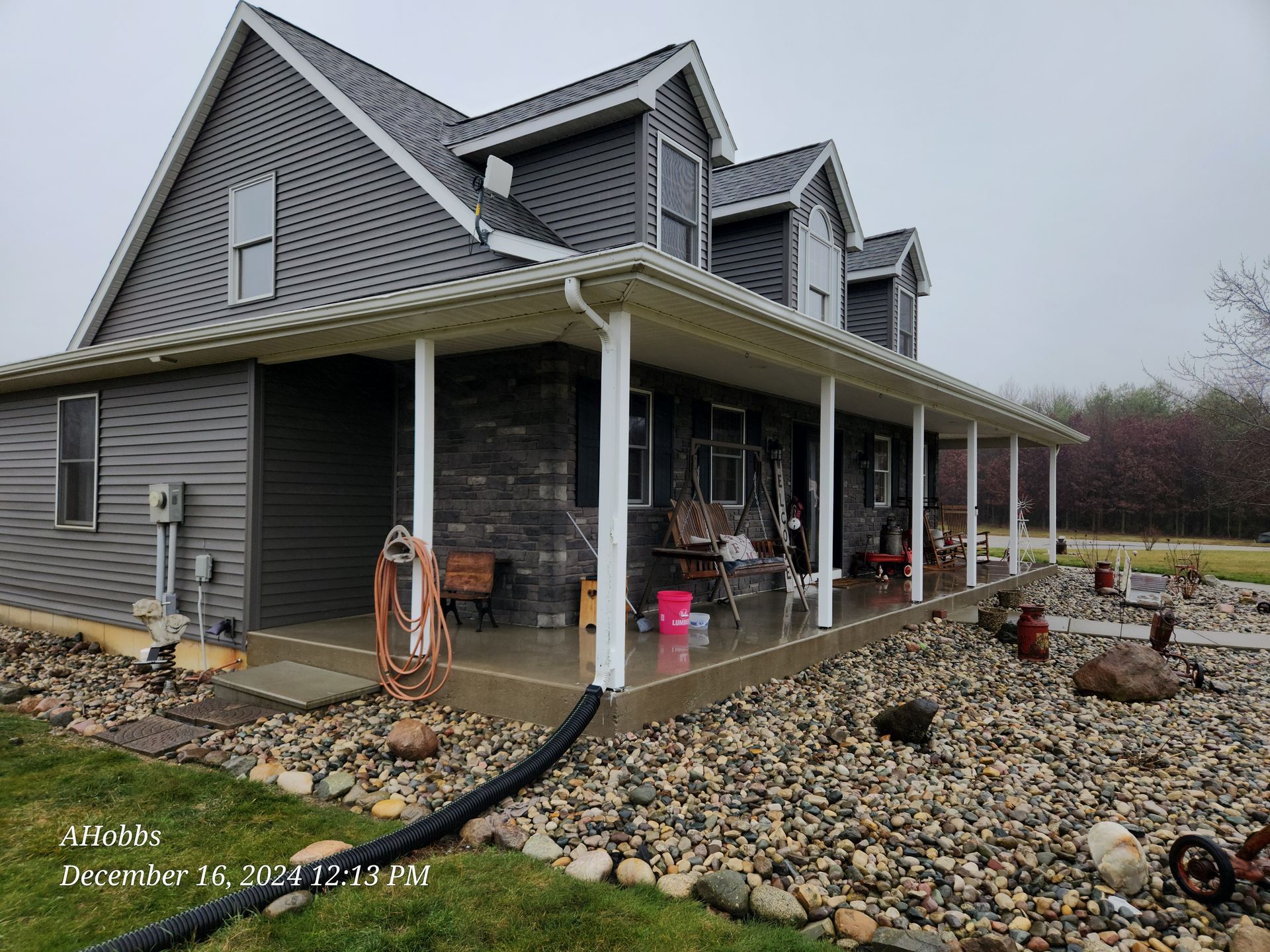 A large house with a porch and rocks in front of it.