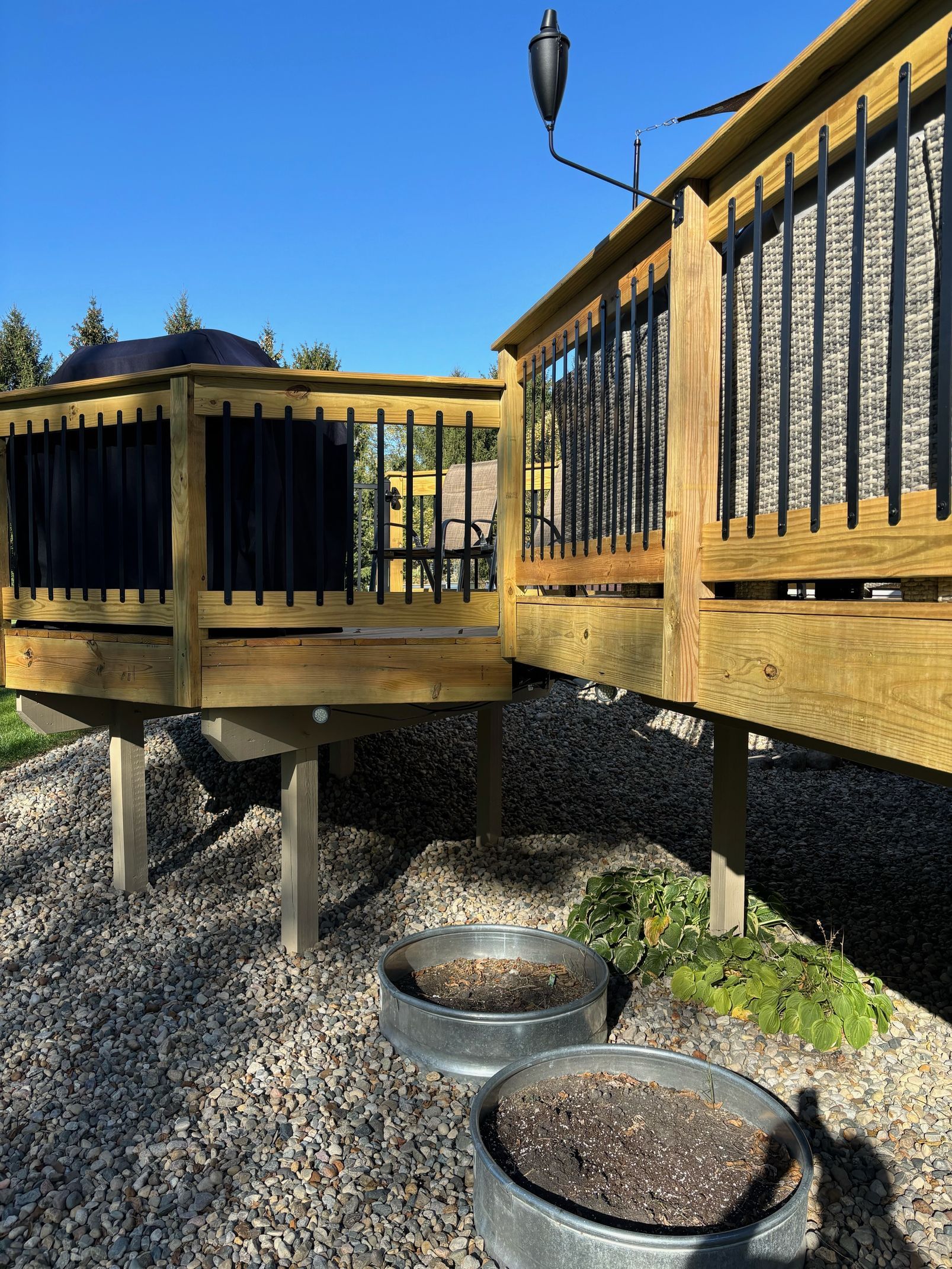 A wooden deck with a metal planter in front of it