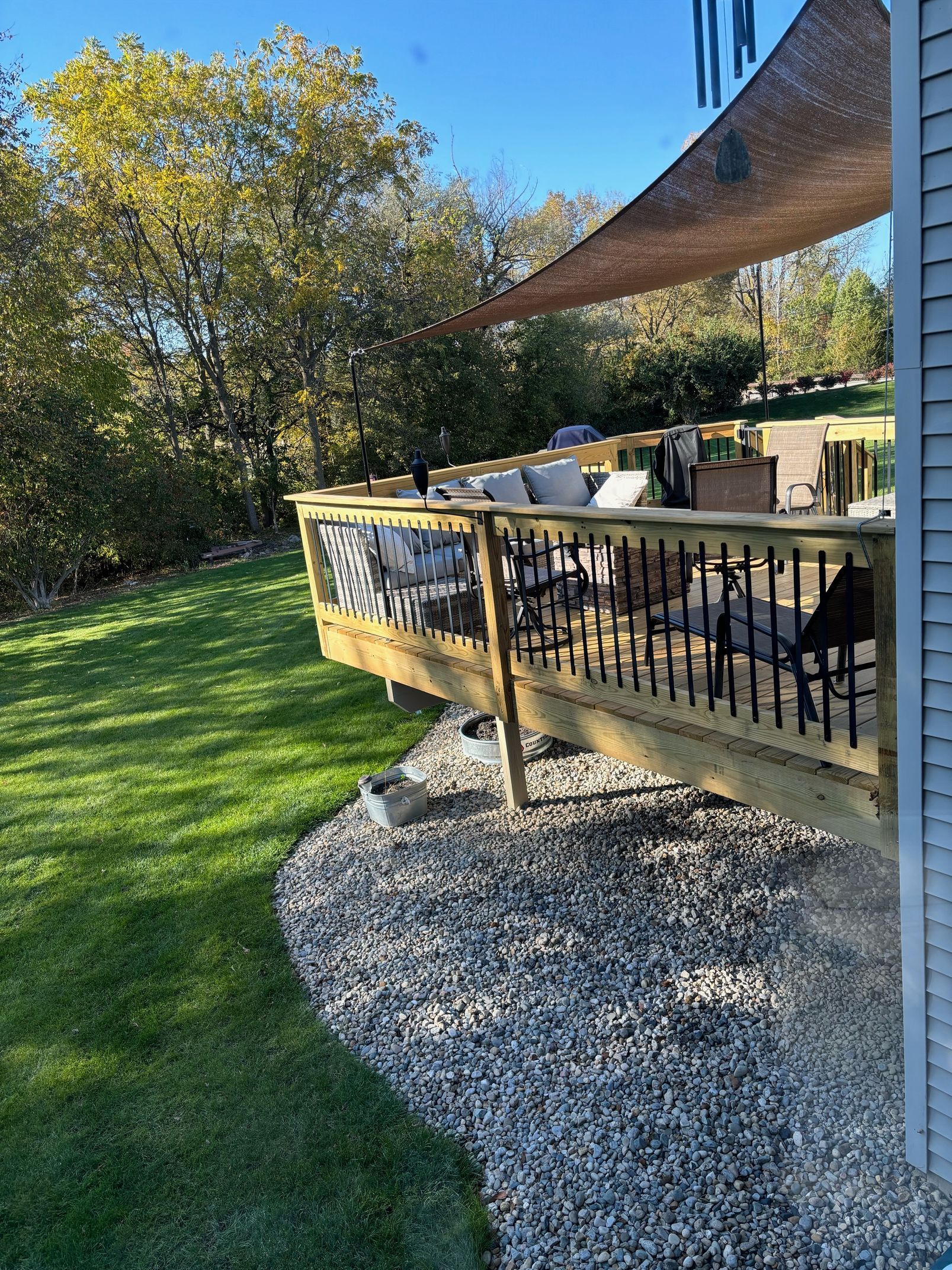 A wooden deck with a couch on it is sitting on top of a lush green lawn.