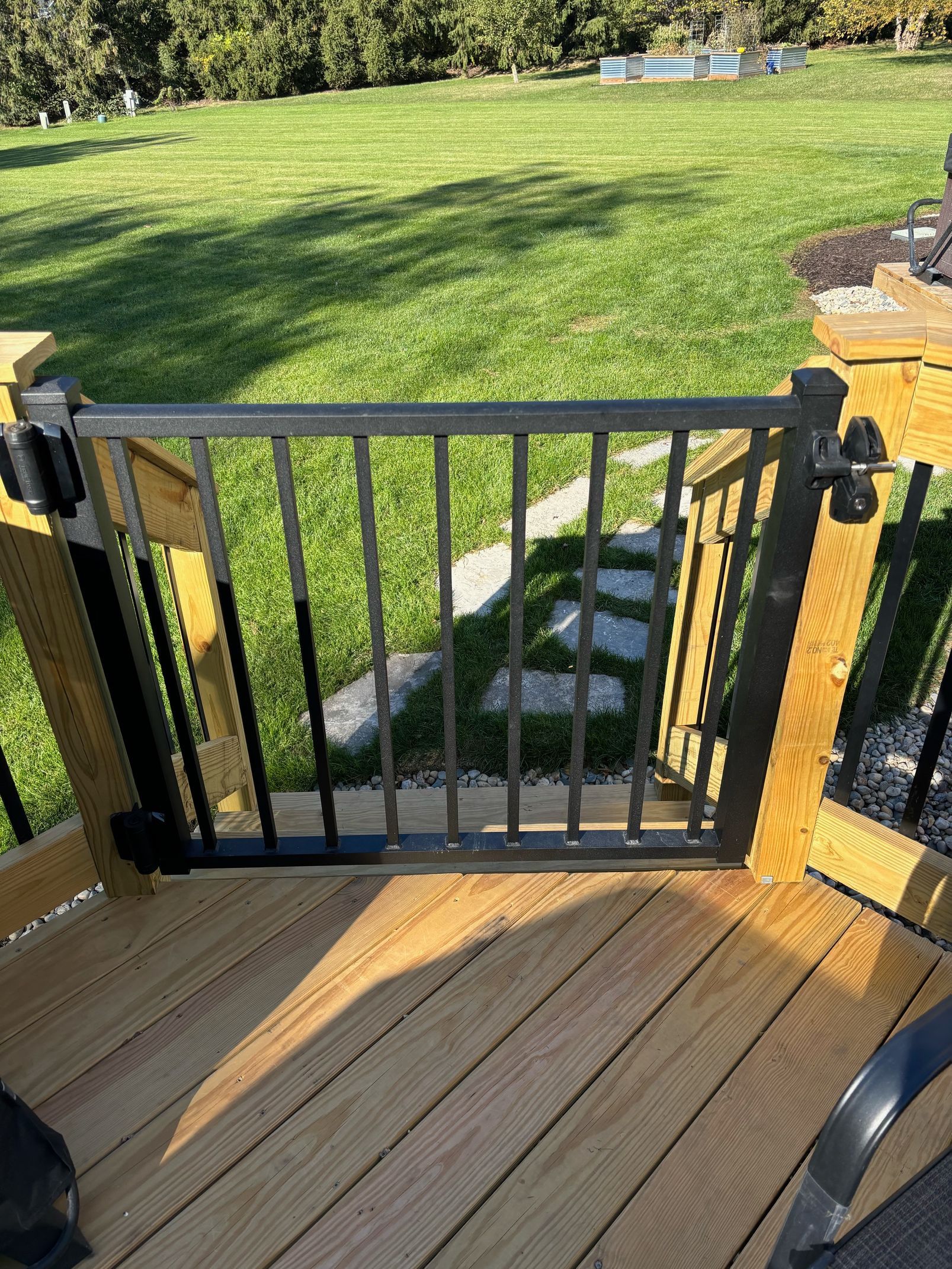A wooden deck with a metal gate leading to a grassy field.