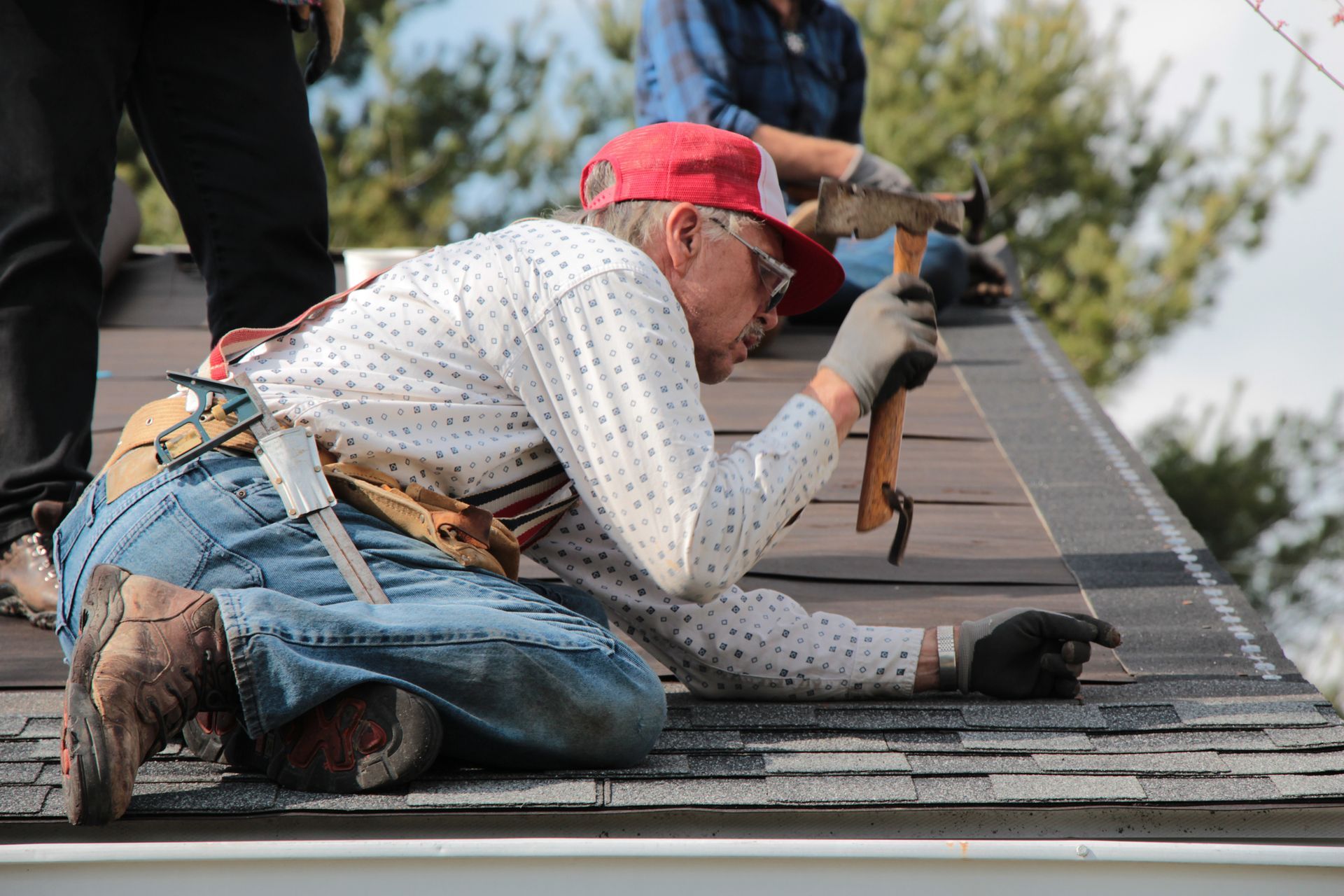 Hammering a nail on the shingles of a roof.