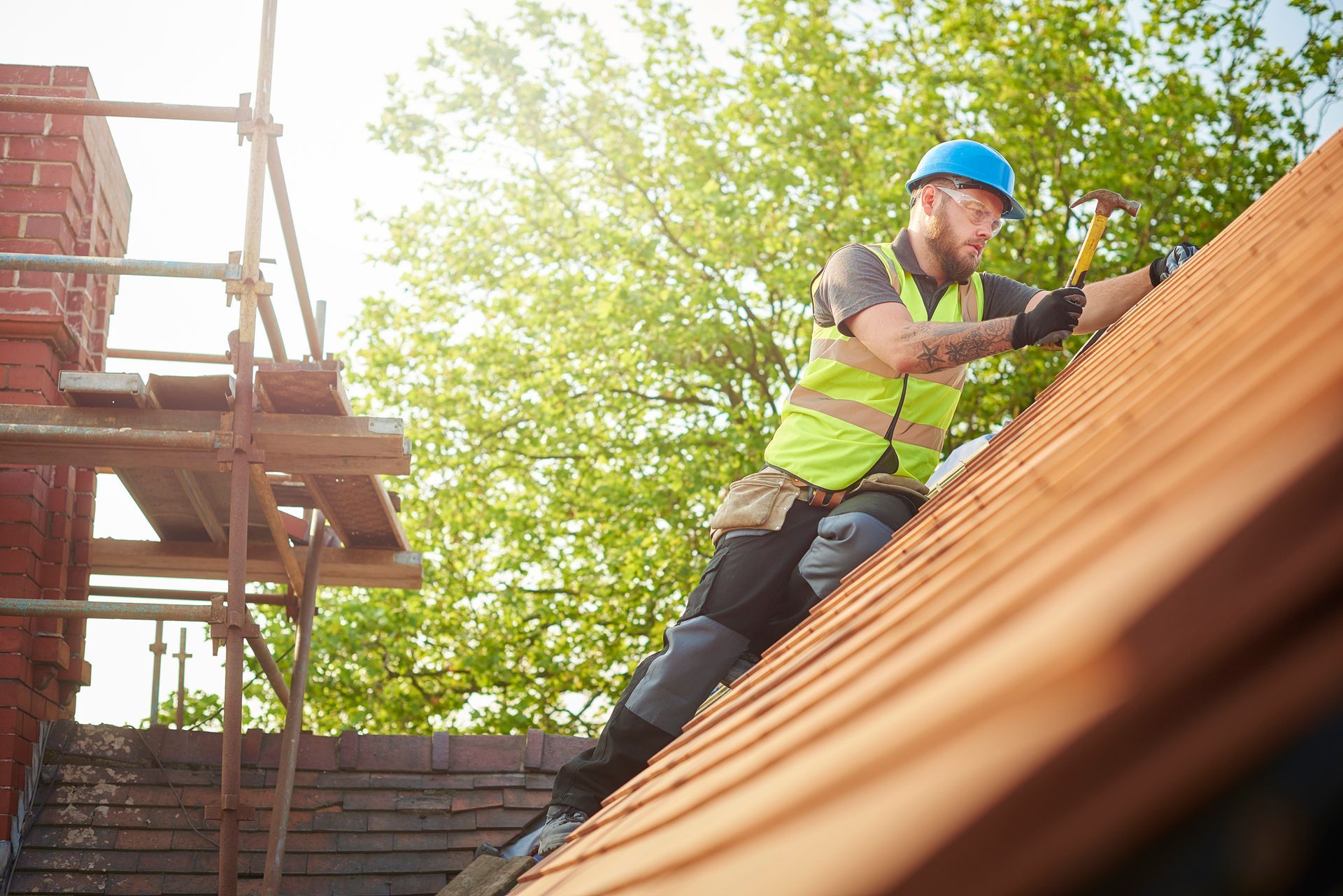 A roofer nails on the roof tiles for a home roof repair.