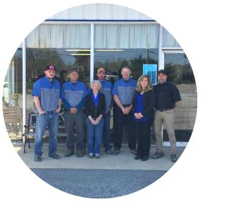 Group of people in blue and gray uniforms in front of a building with glass windows.