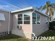 A mobile home with a lot of windows and a palm tree in the background.