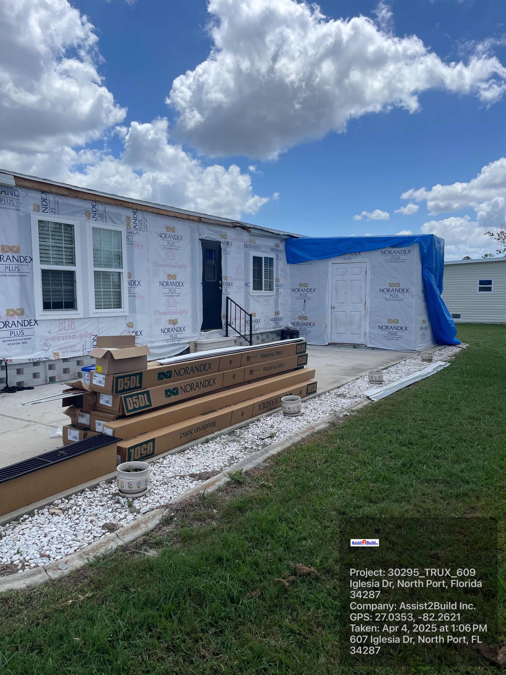 A mobile home is being built with a blue tarp over it.