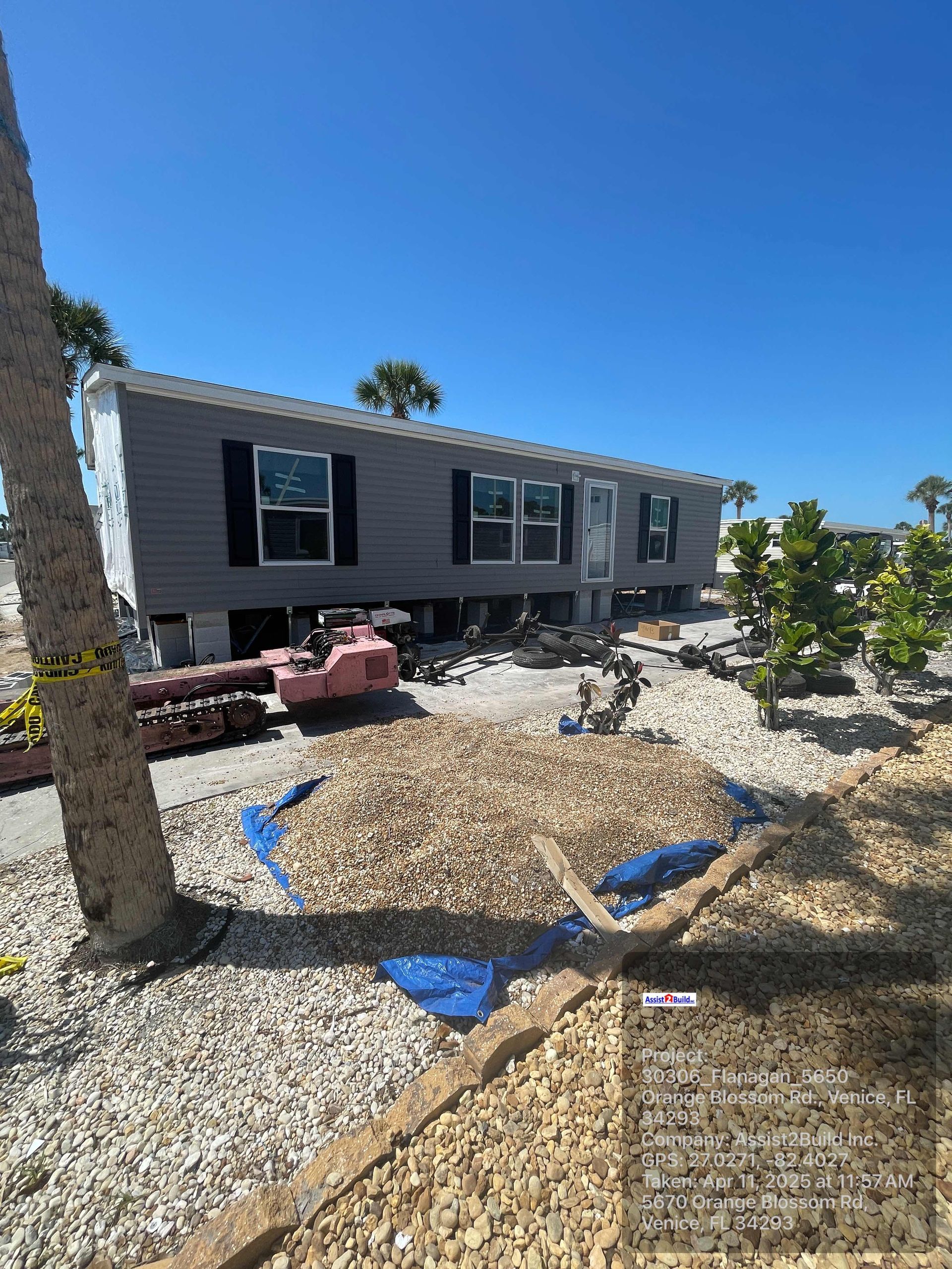 A mobile home is sitting on top of a pile of gravel in a yard.