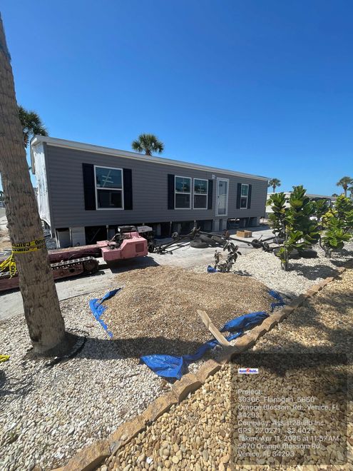 A mobile home is sitting on top of a pile of gravel in a yard.