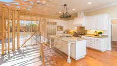 A kitchen in a house under construction with white cabinets and granite counter tops.