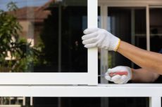 A man is fixing a window with a screwdriver.