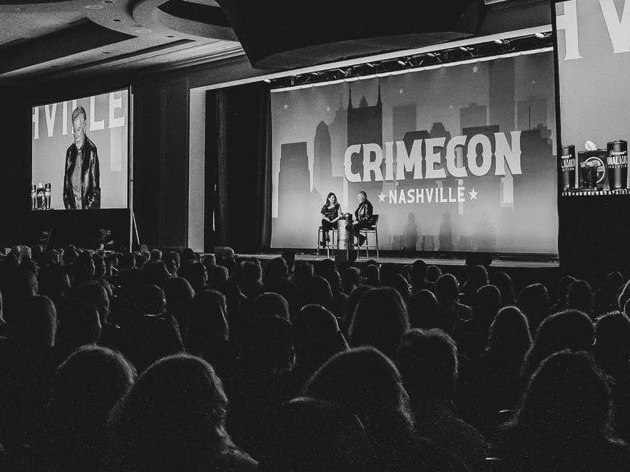 A crowd of people are sitting in front of a large screen that says crimecon nashville.