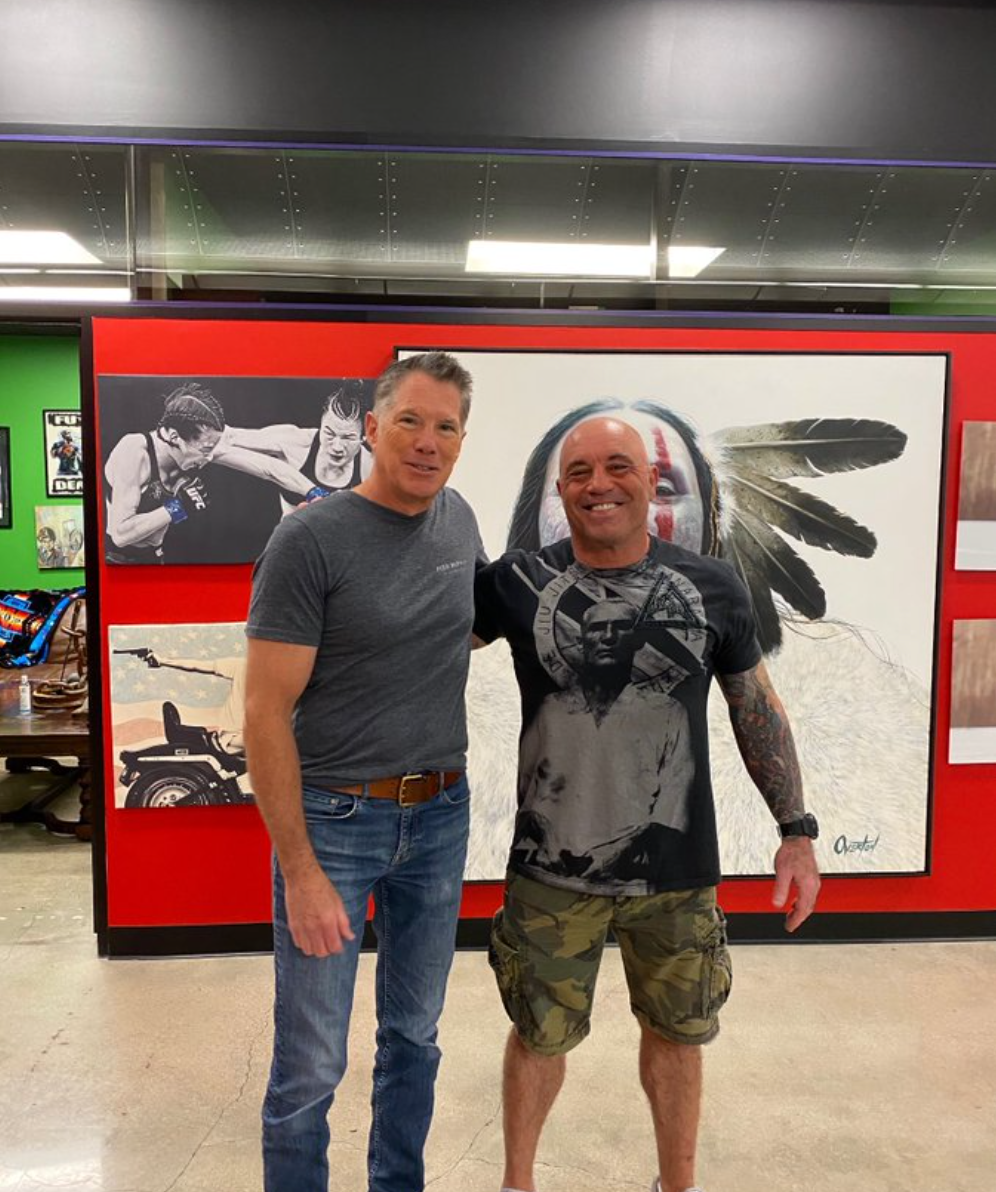 Two men are posing for a picture in front of a painting