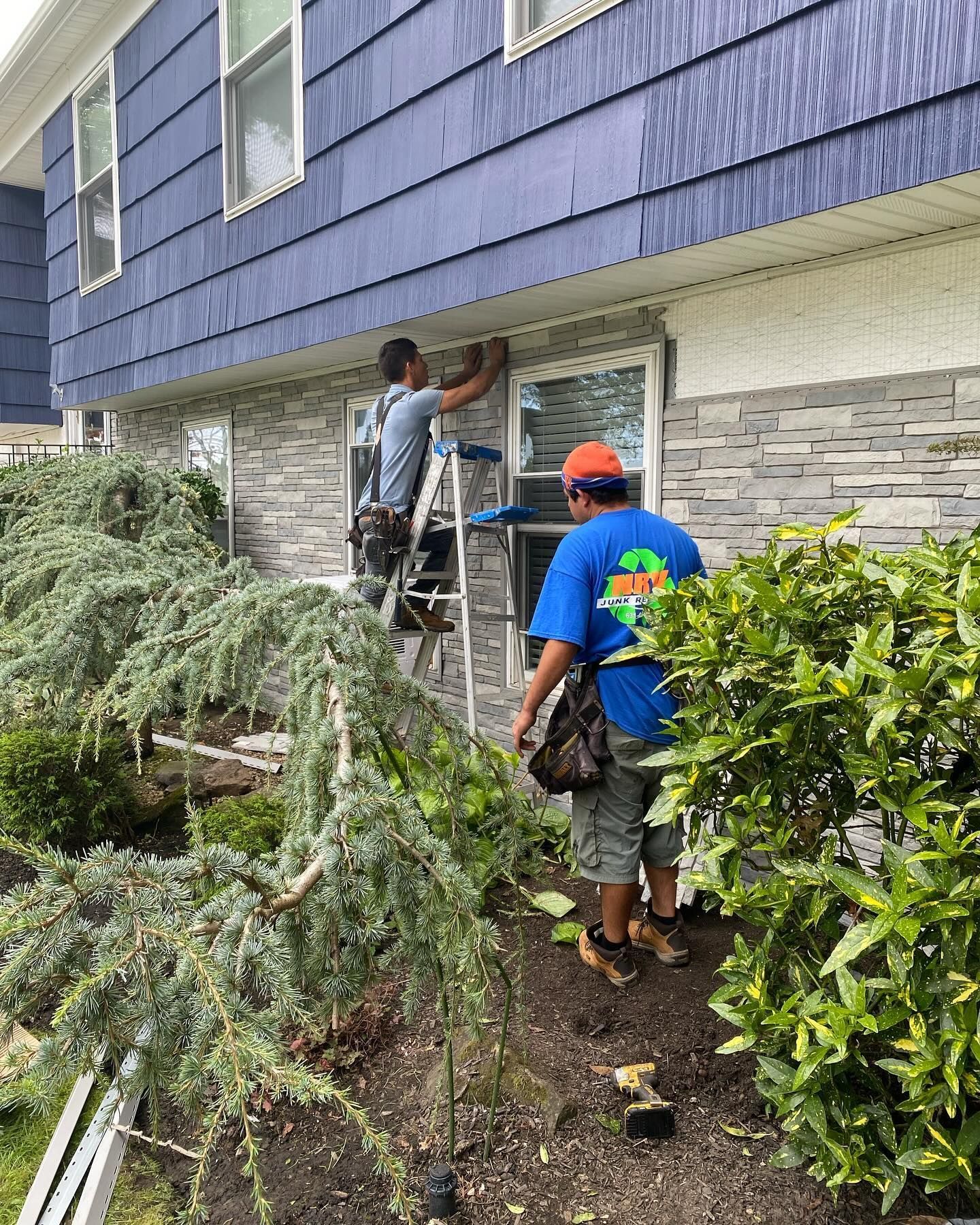 Two men are working on the side of a house.