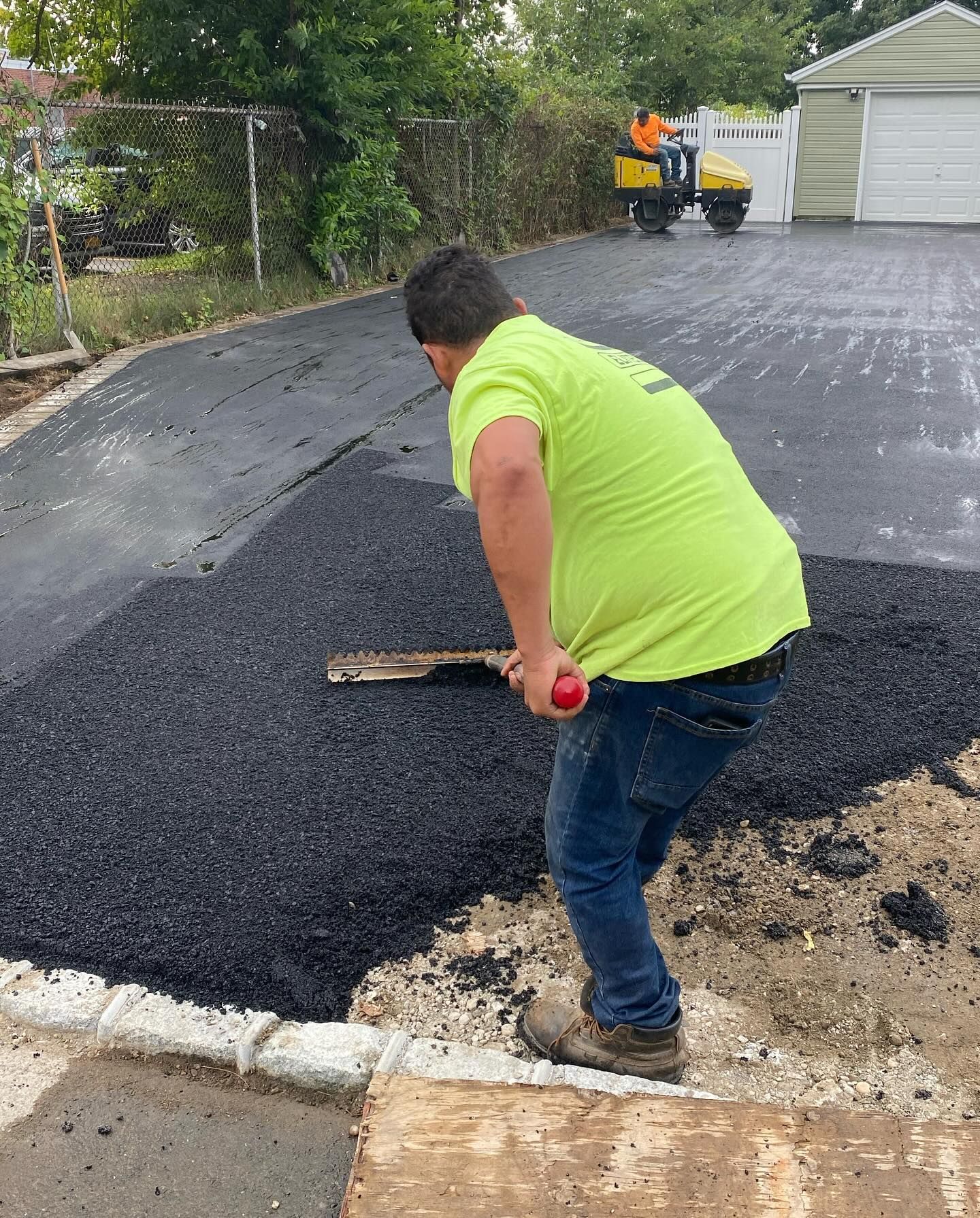 A man is working on a driveway with a shovel.