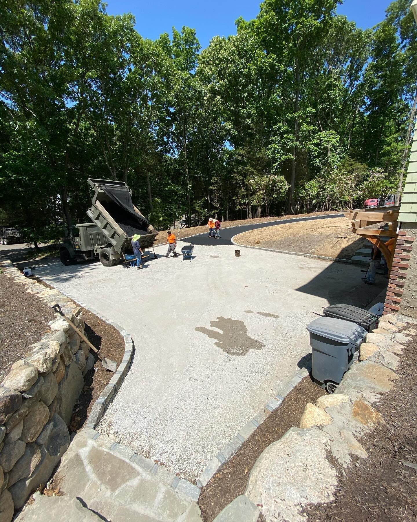 A group of people are working on a driveway in the woods.