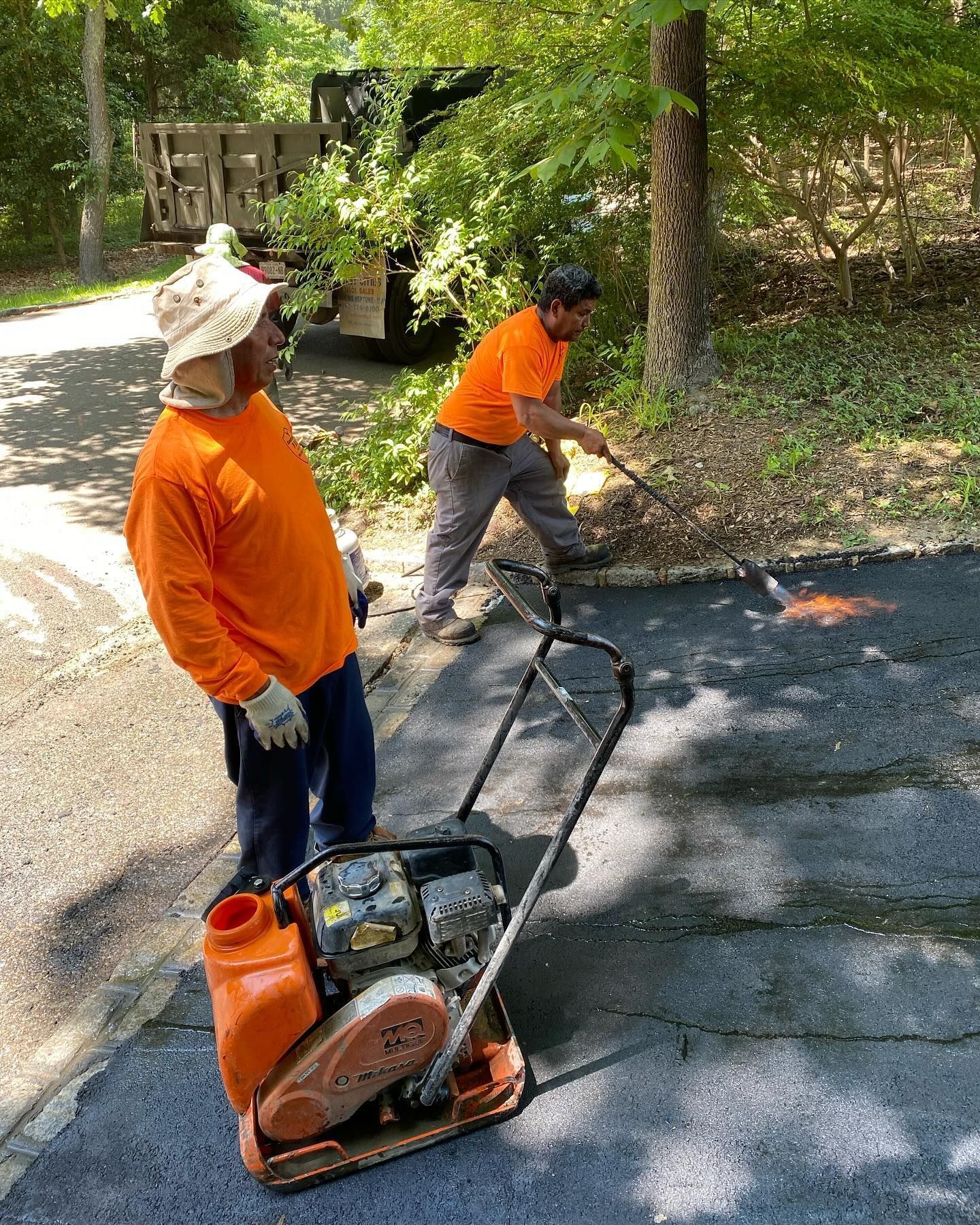 Two men are working on a driveway with a machine.
