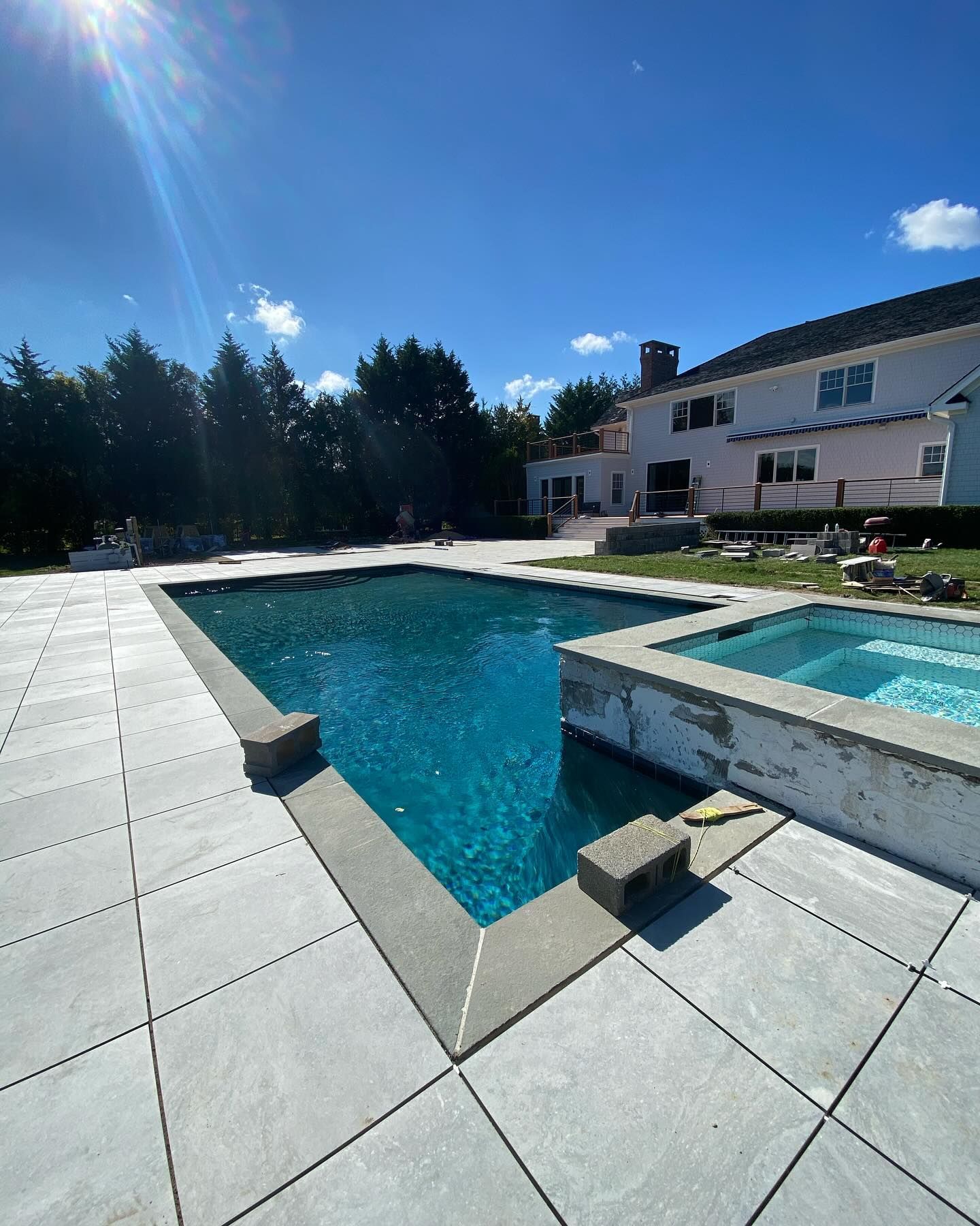 There is a large swimming pool in the backyard of a house.