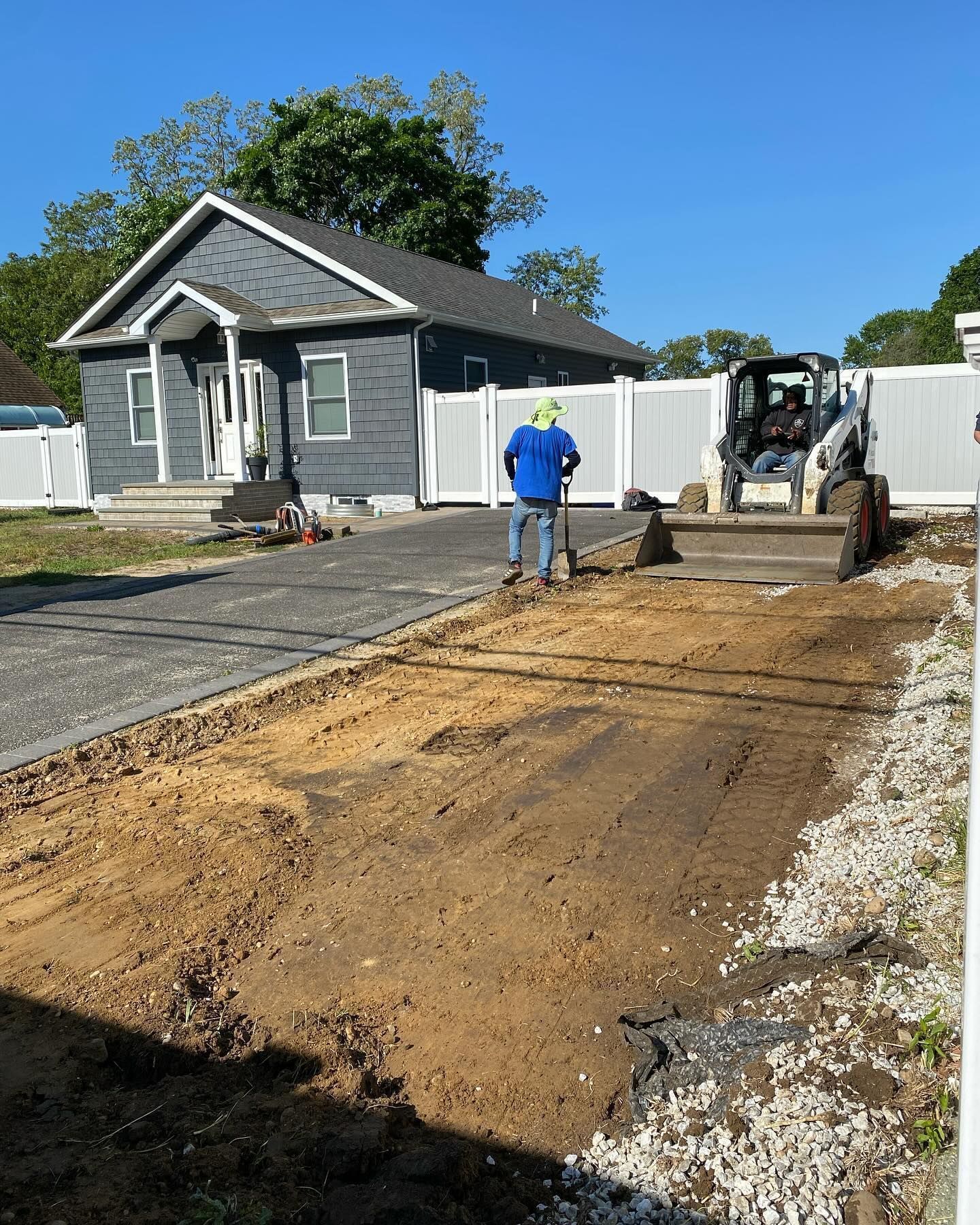 A man is standing in the dirt in front of a house.