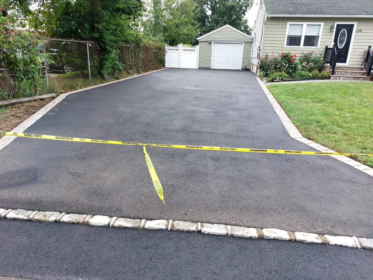 A driveway with a yellow line on the side of it and a house in the background.