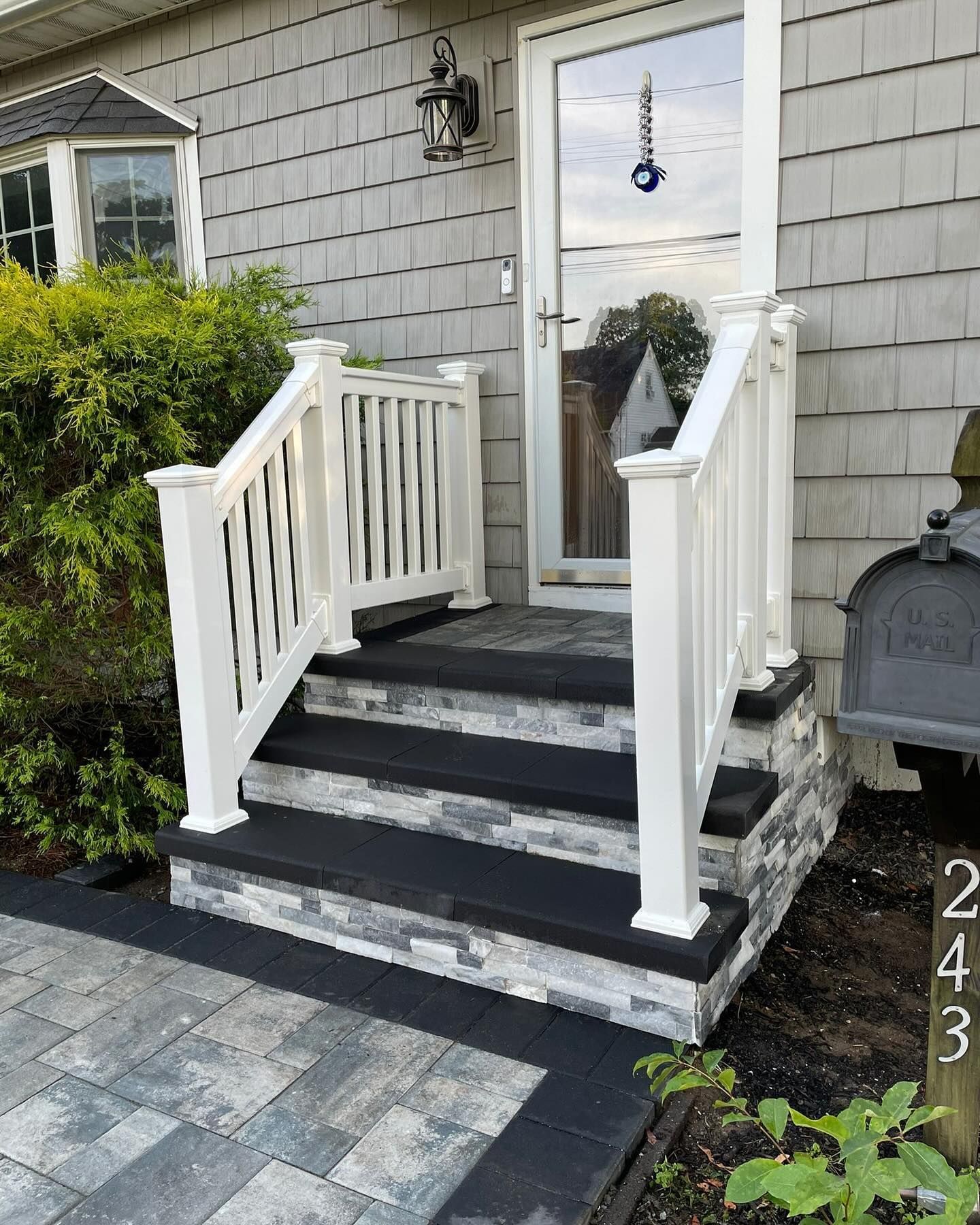 A white porch with black steps and a white railing is in front of a house.