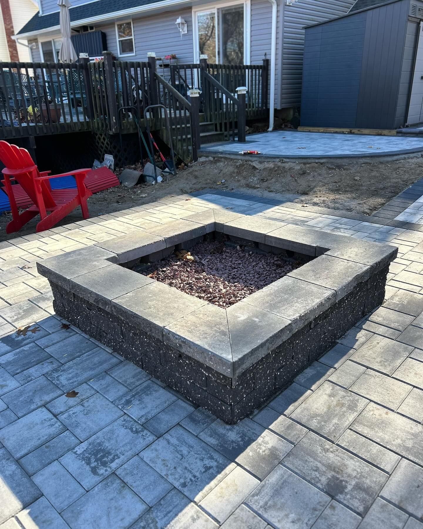 A fire pit is sitting on top of a brick patio next to a house.