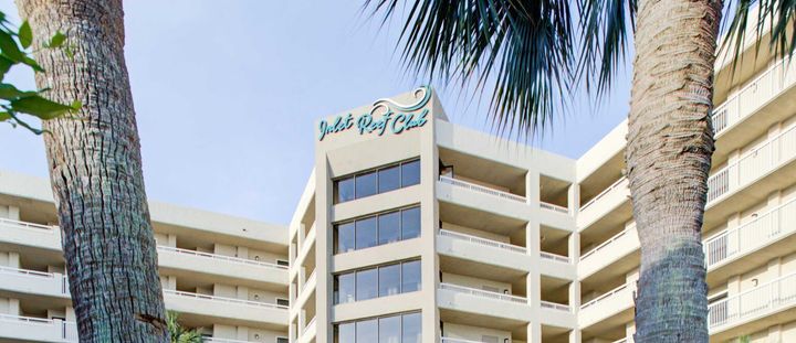 A large building with a lot of windows is surrounded by palm trees.