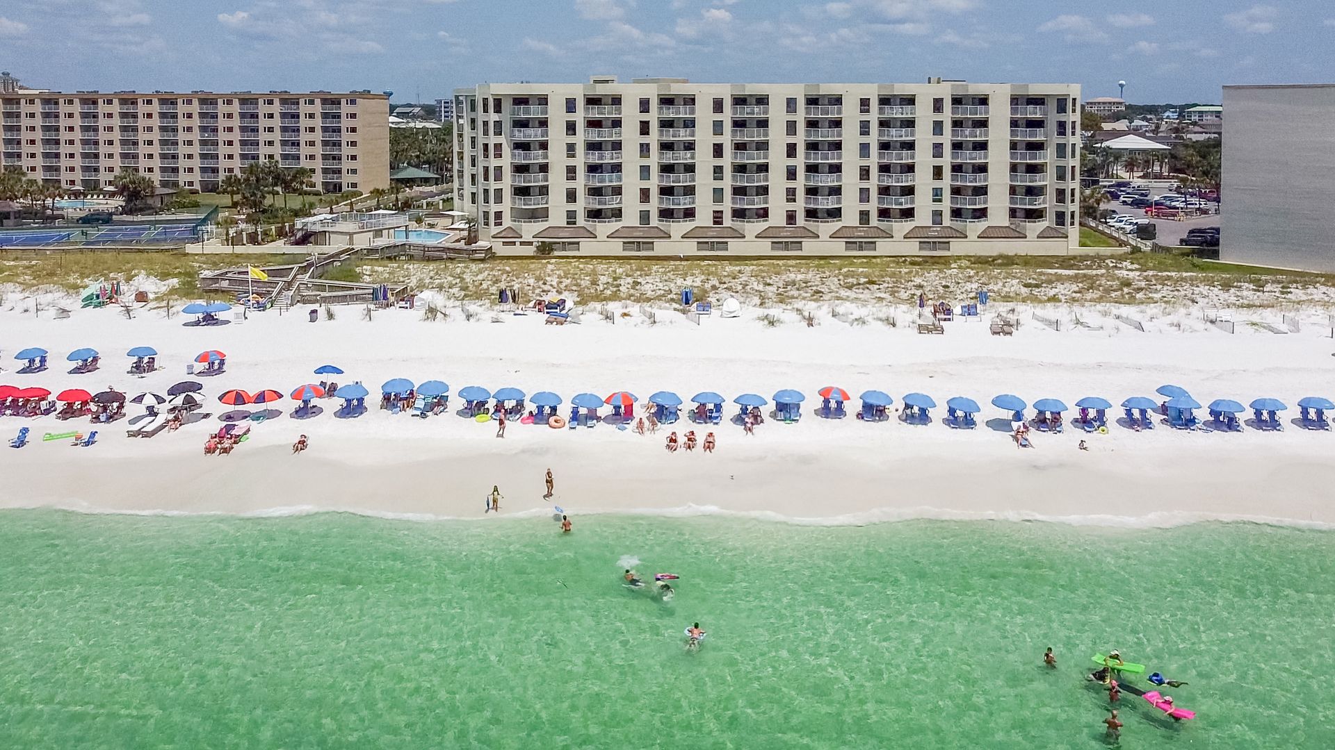 An aerial view of a beach with a large building in the background.