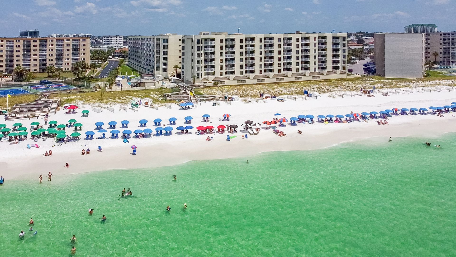 An aerial view of a beach filled with people and umbrellas.