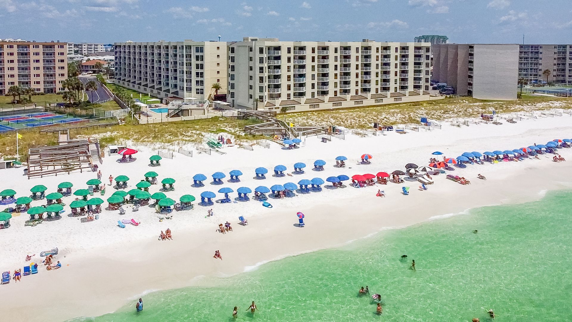 An aerial view of a beach filled with people and umbrellas.