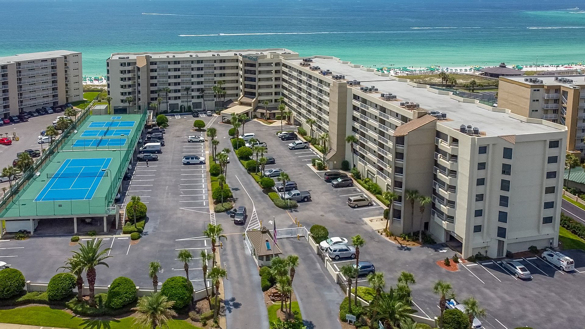 An aerial view of a large apartment complex with a tennis court in the middle.