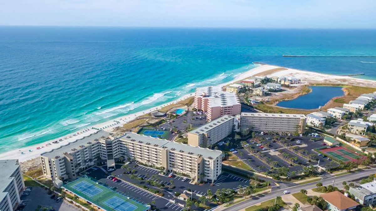 An aerial view of a beach resort with lots of buildings and a tennis court.