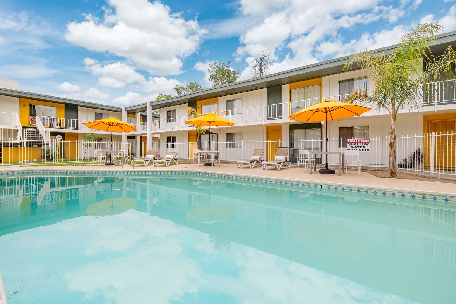 a swimming pool surrounded by chairs and umbrellas with a sign that says caution shallow water