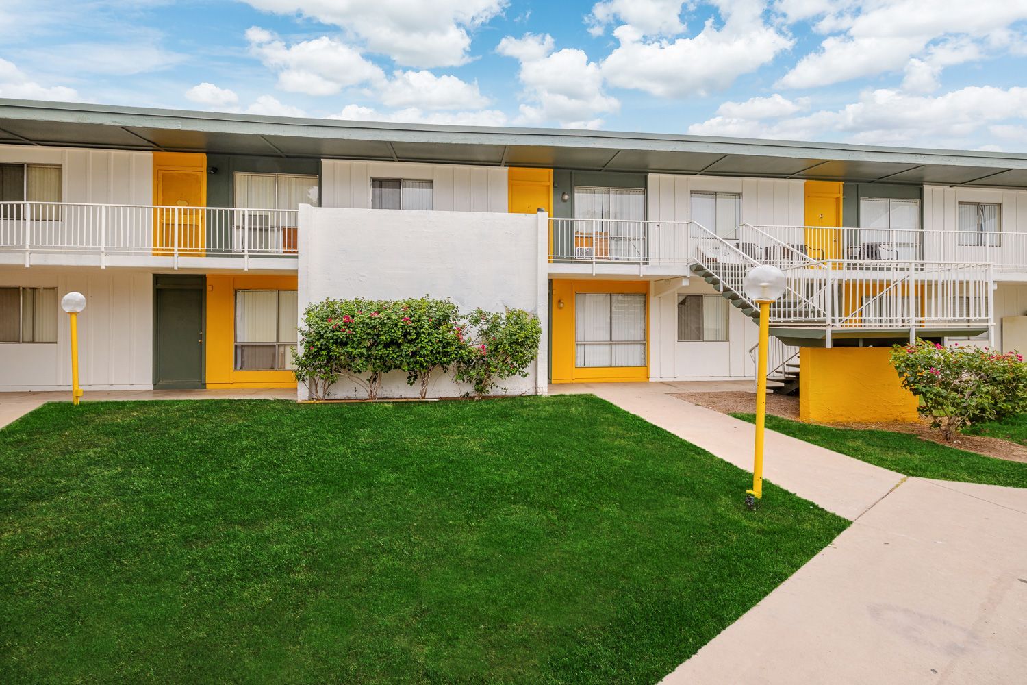 a white and yellow apartment building with stairs leading up to the second floor