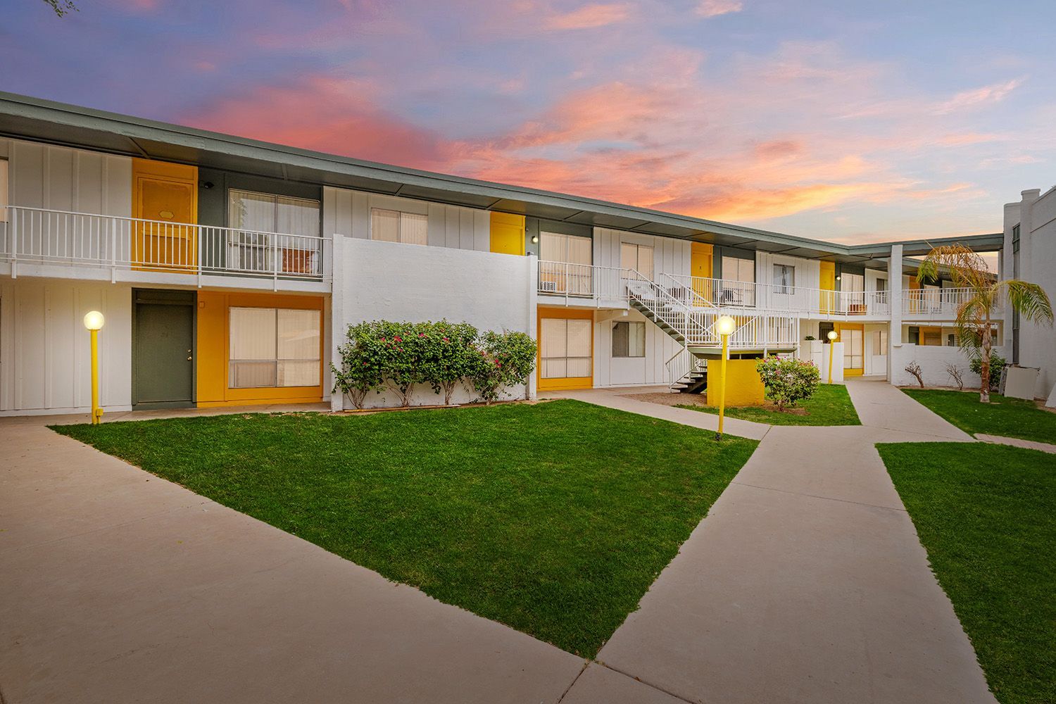 a white and yellow apartment building with a sunset in the background