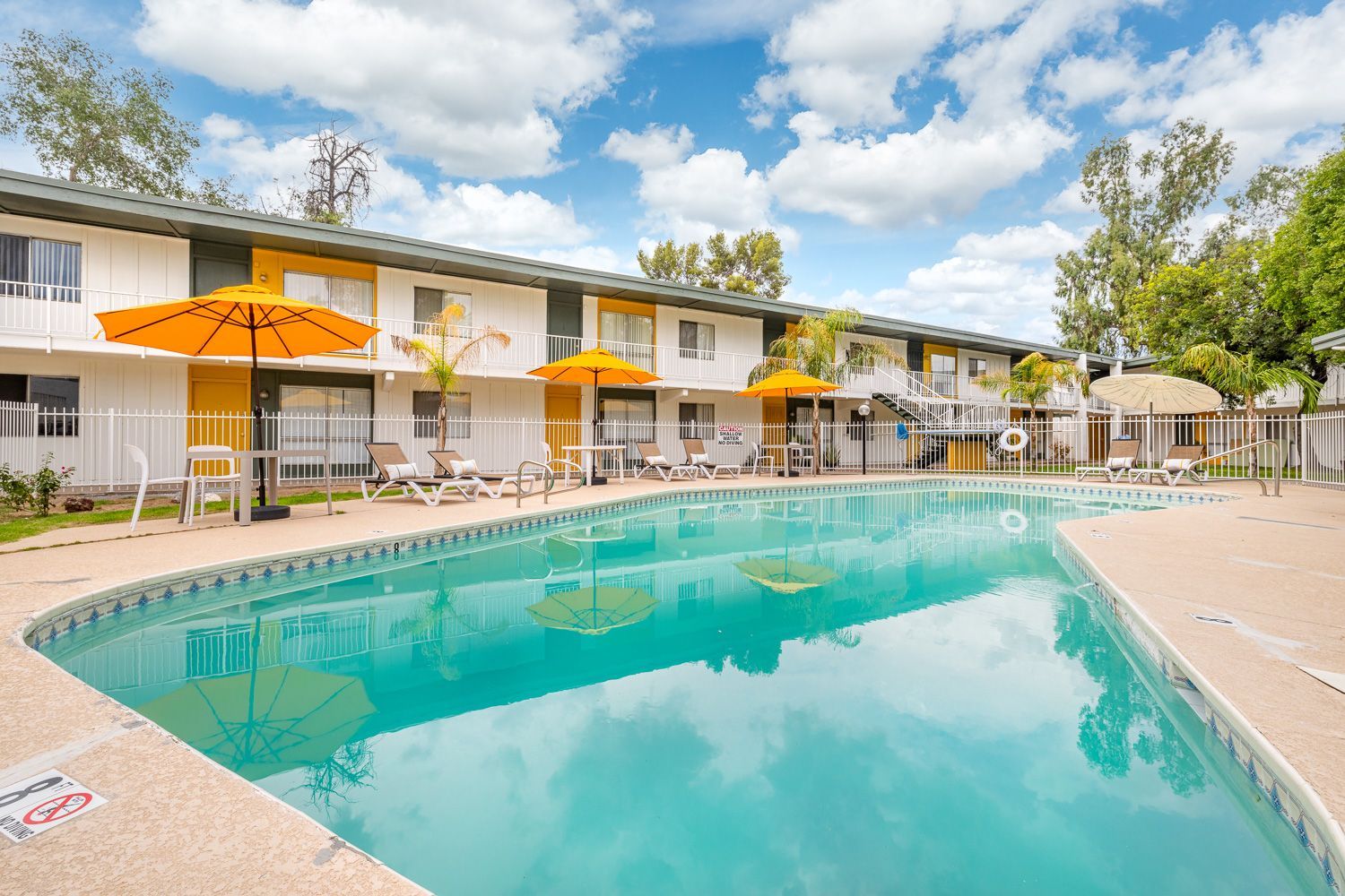 a swimming pool in front of a building with umbrellas and chairs