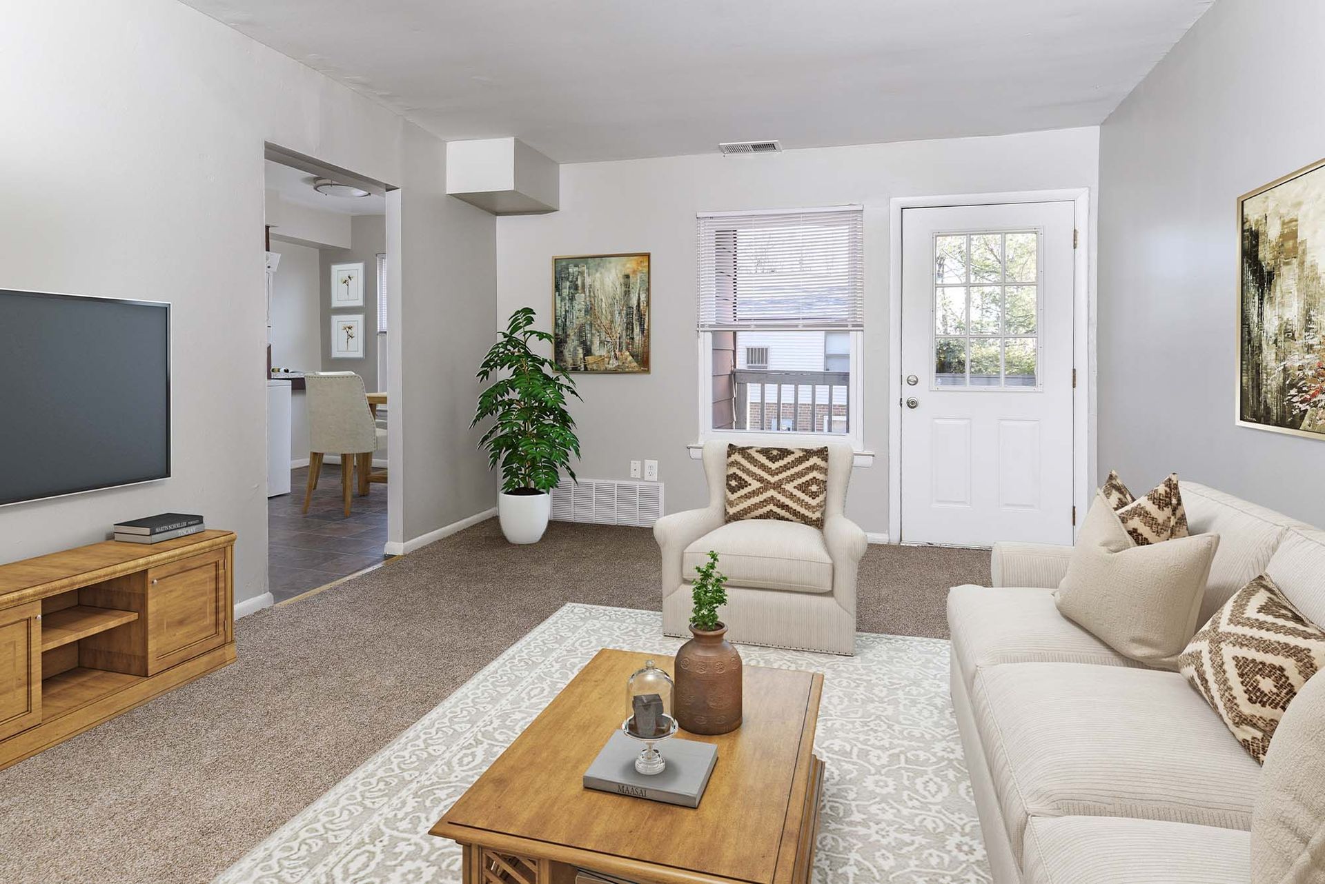 Living room in an apartment with beige seating, a coffee table, and a front door.