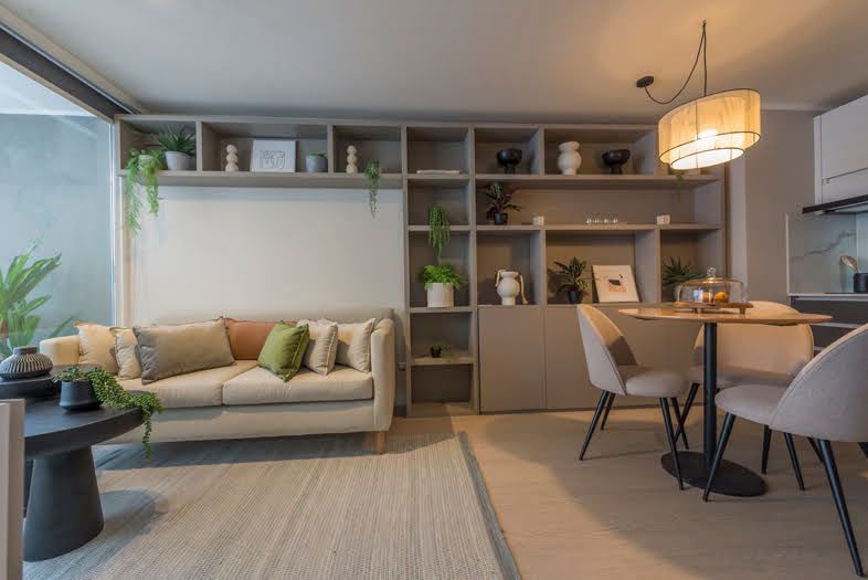 Sala de estar con sofá beige, estantería empotrada, mesa de comedor redonda y alfombra.