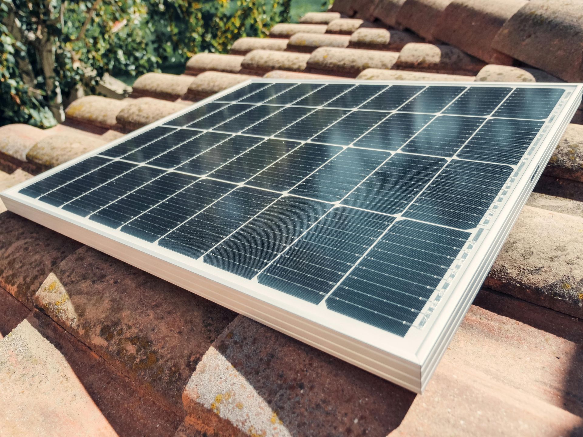 A solar panel is sitting on top of a tiled roof.