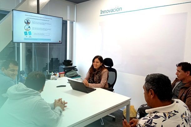 Un grupo de personas está sentada alrededor de una mesa con un ordenador portátil.