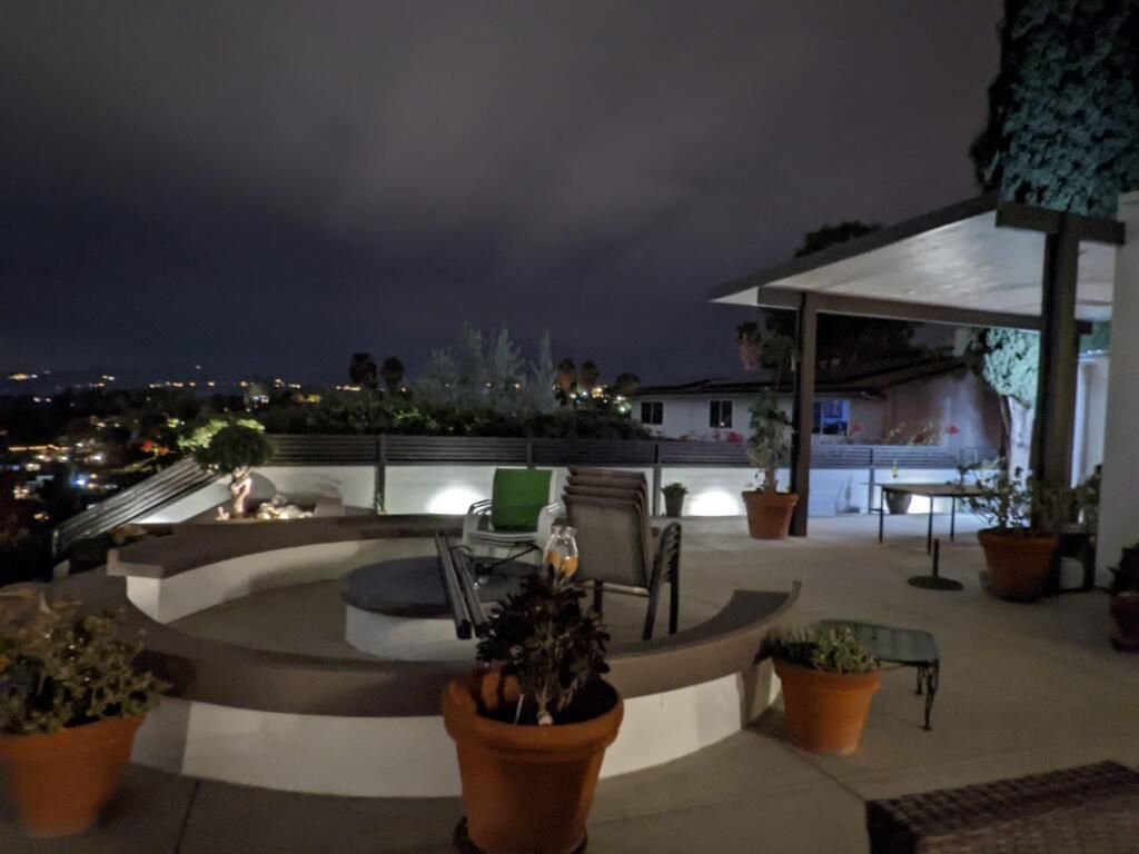 A patio with potted plants and chairs at night