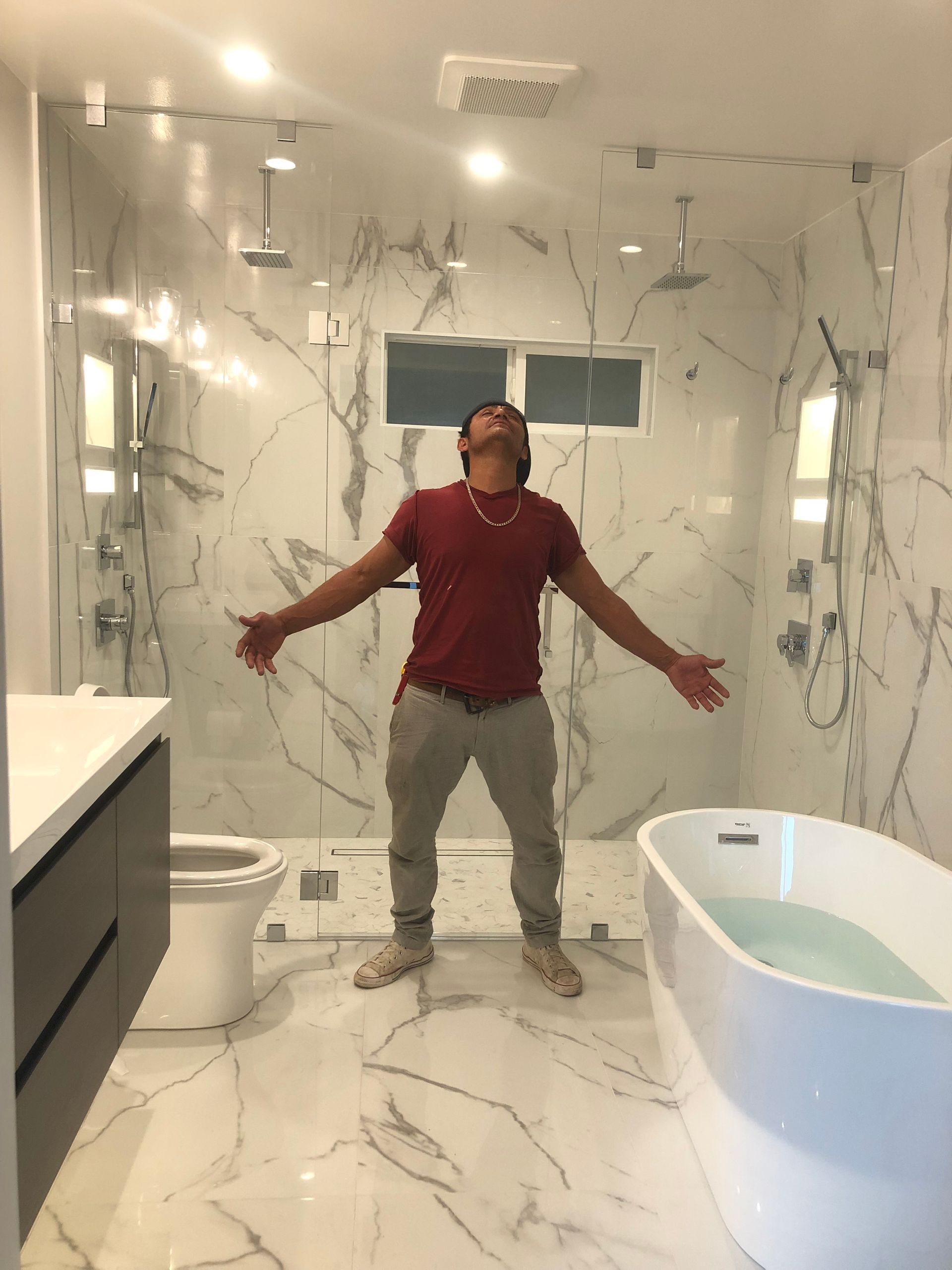 A man is standing in a bathroom with his arms outstretched.