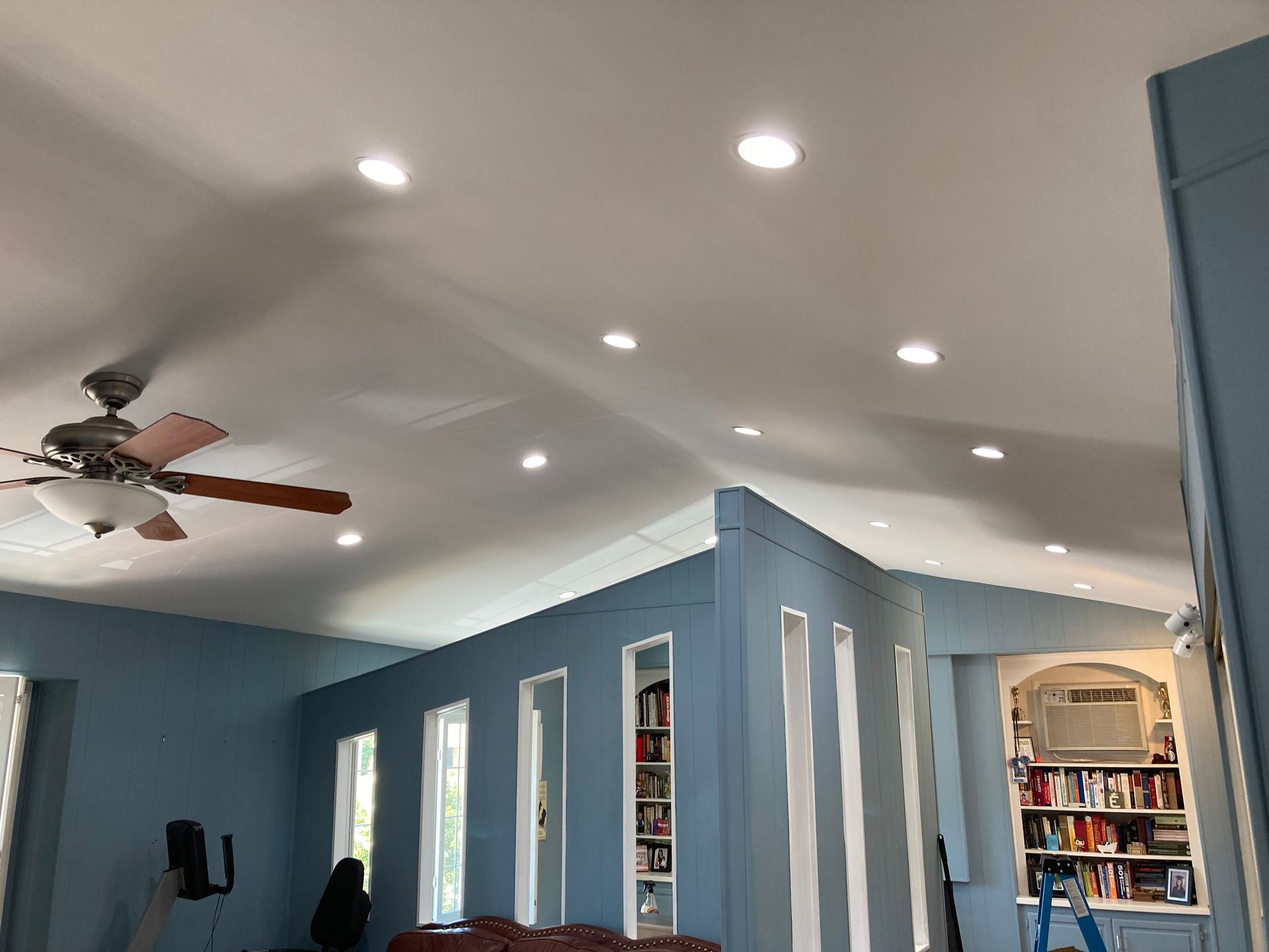 A living room with blue walls and a ceiling fan.