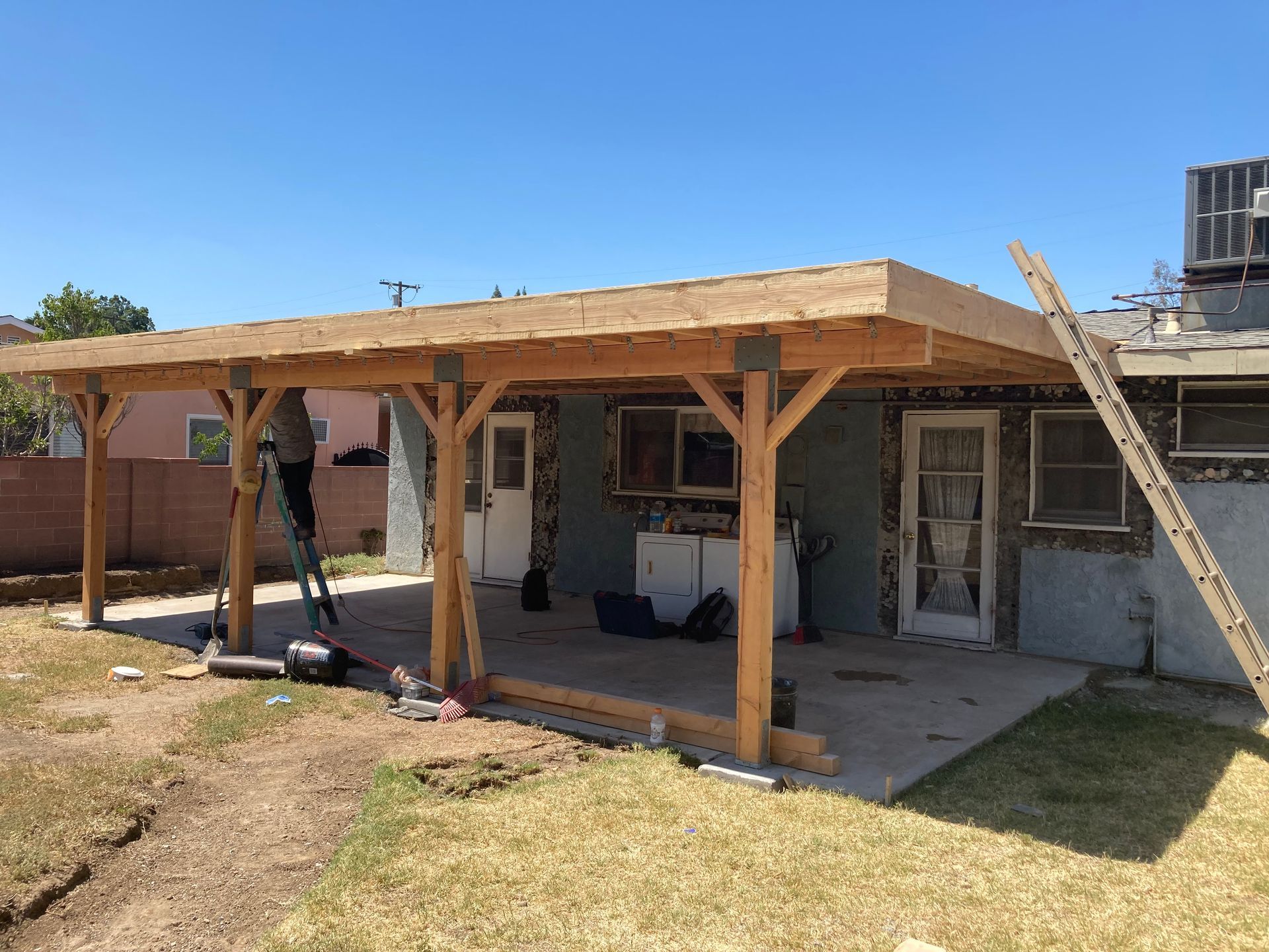 A wooden structure is being built in the backyard of a house.