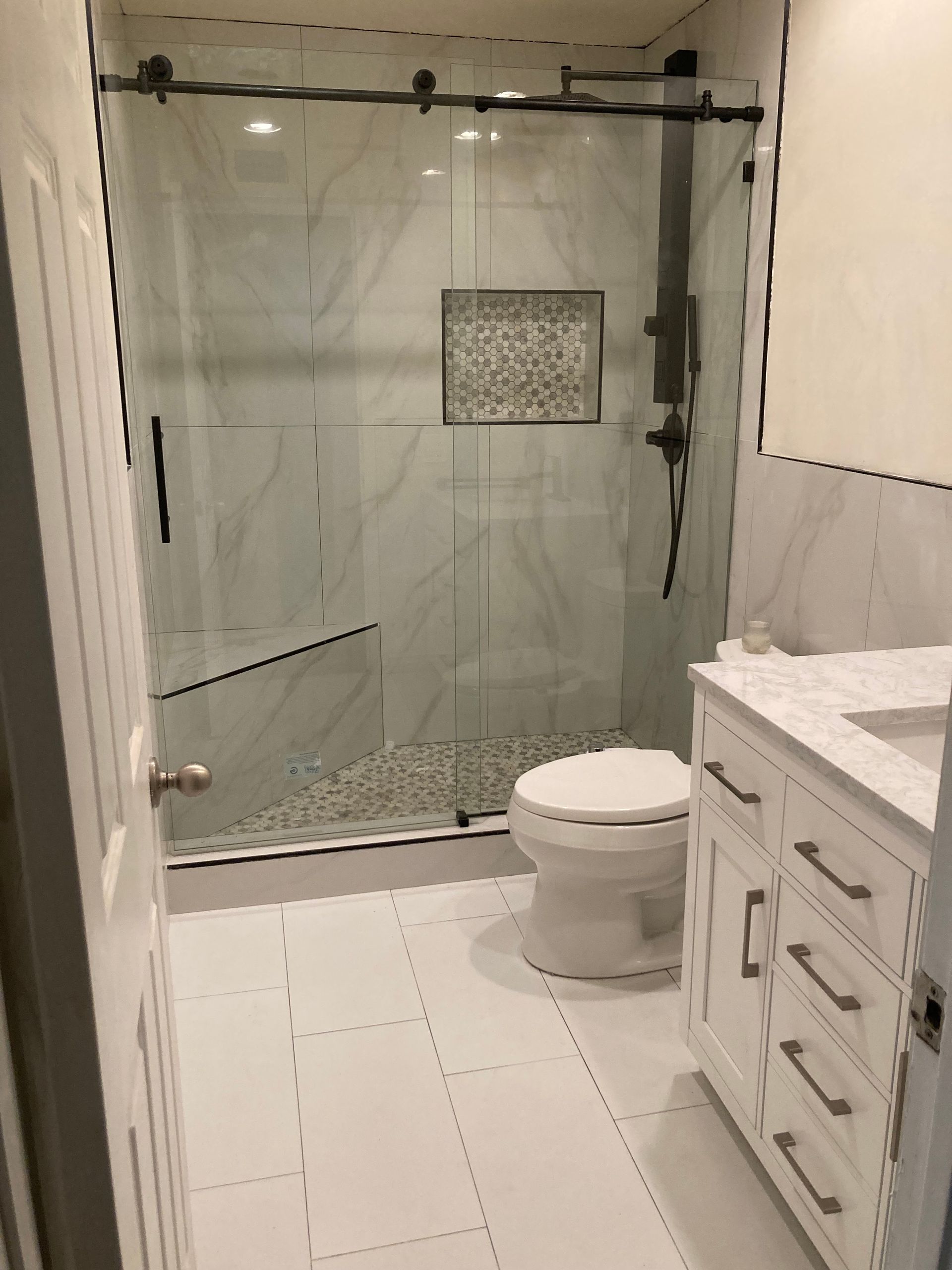 A bathroom with a toilet , sink and shower.